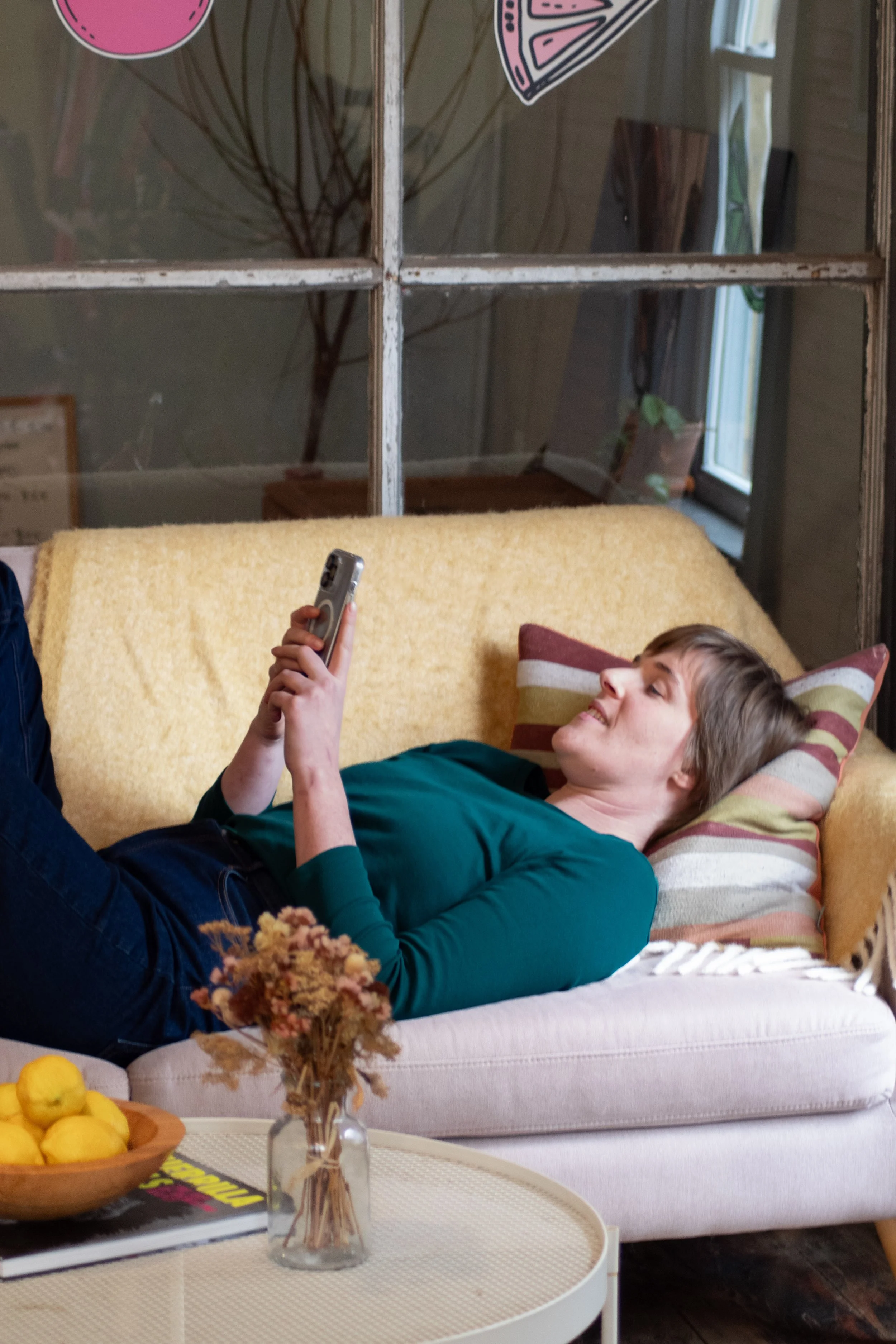 Emily, a marketing specialist, is laying on a couch looking at her phone