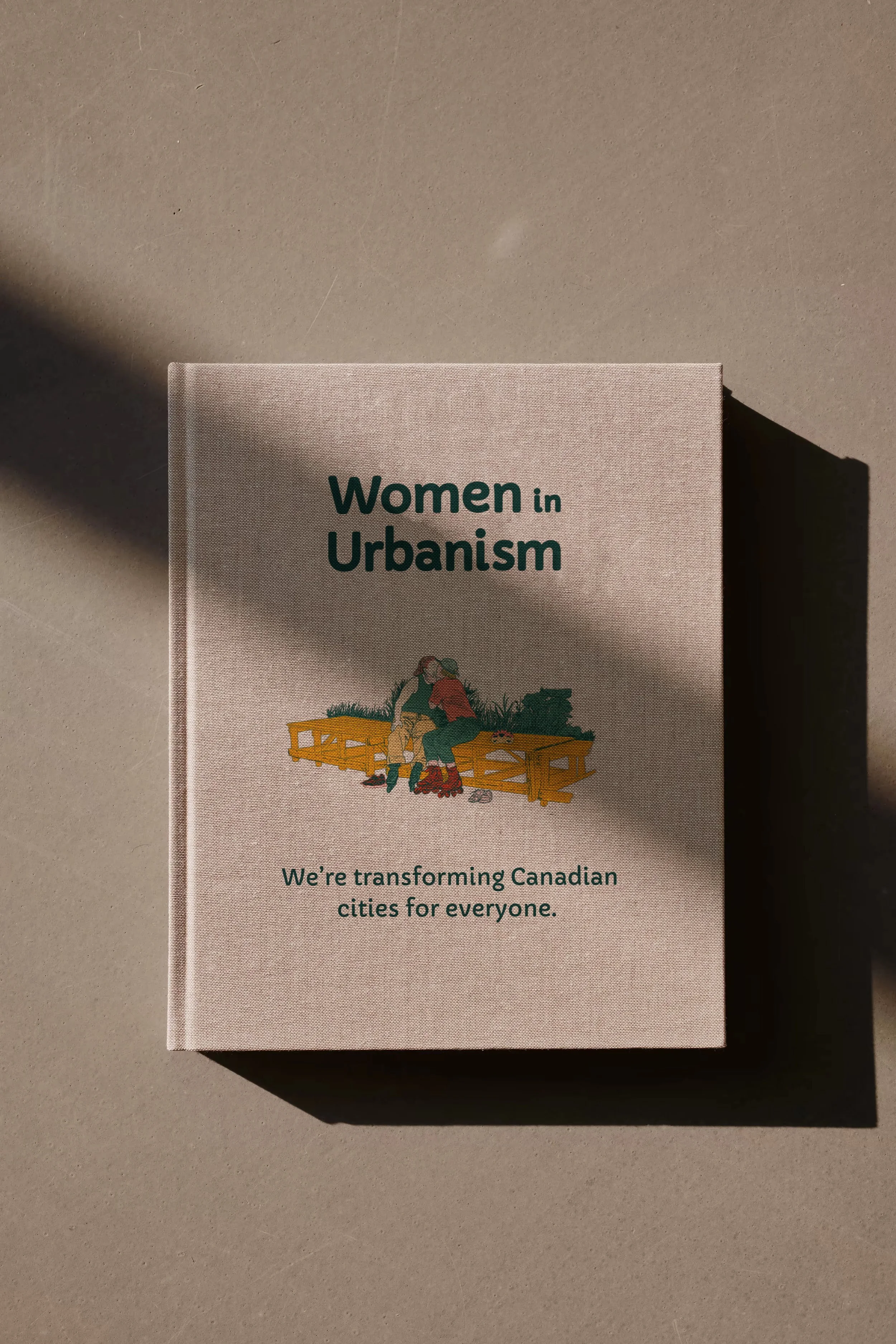 A notebook titled "Women in Urbanism" with a subtitle that says "We're transforming Canadian cities for everyone". The cover features an illustration of women sharing a kiss on a park bench.