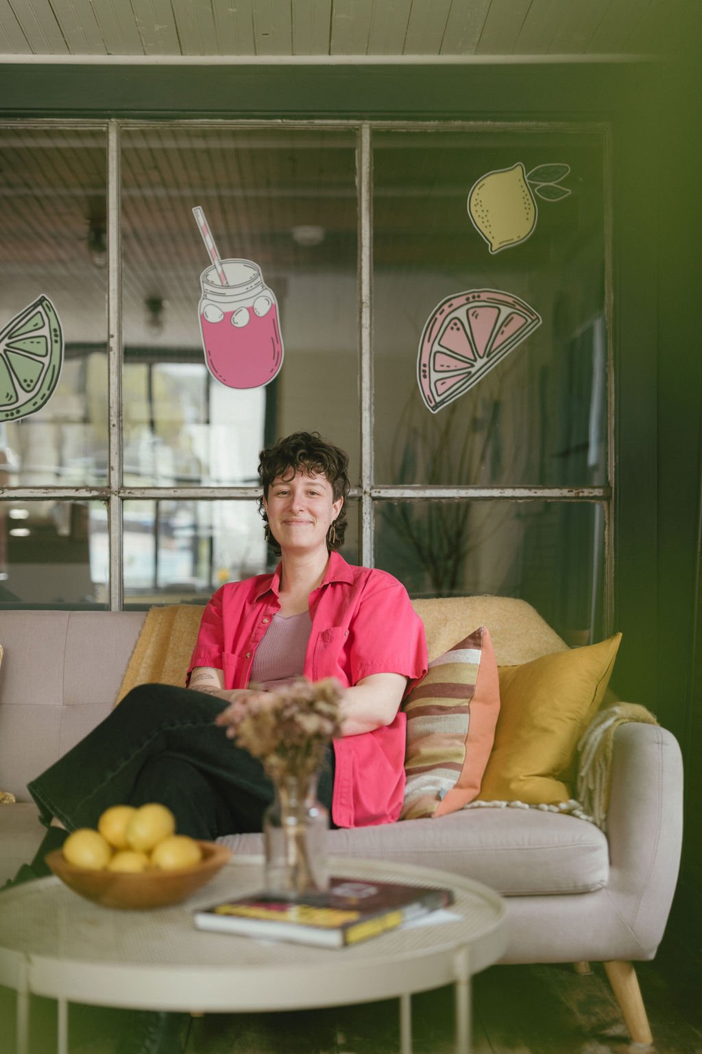 Meghan, a brand and website designer, is sitting on a couch in her office