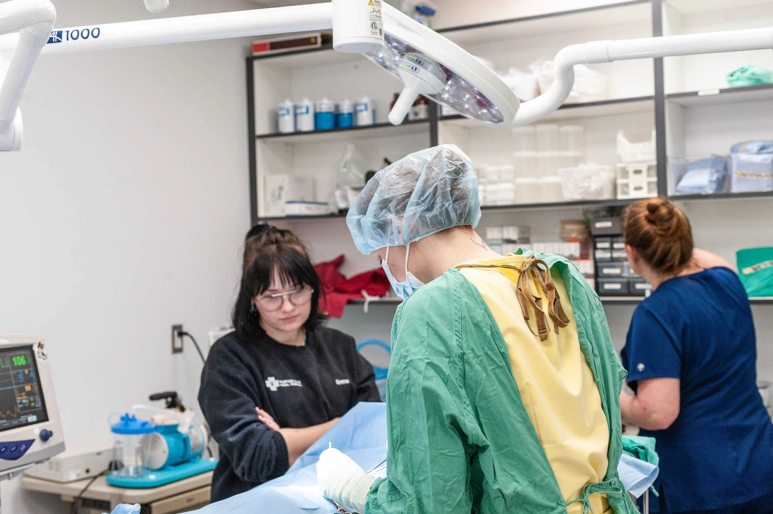 Medical professionals performing surgery in an operating room with surgical lights, monitors, and medical supplies.