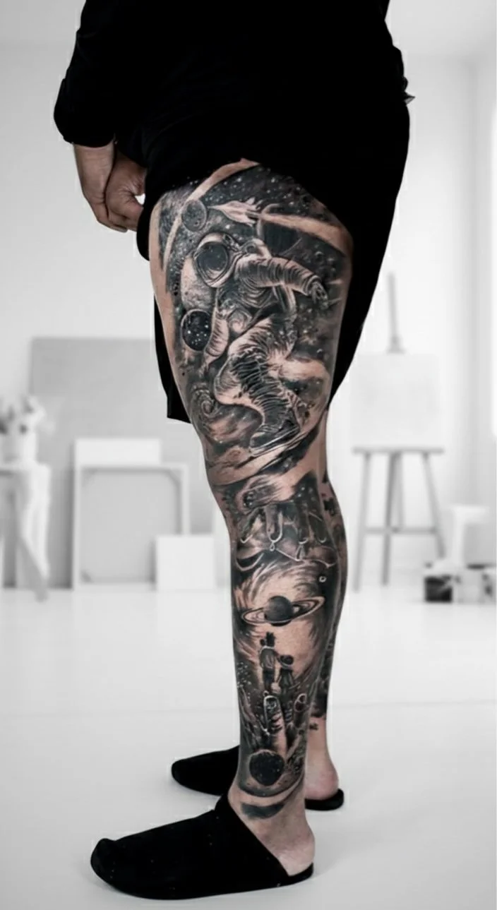Black and gray space-themed tattoo sleeve featuring an astronaut, planets, a child holding a balloon, and cosmic elements.