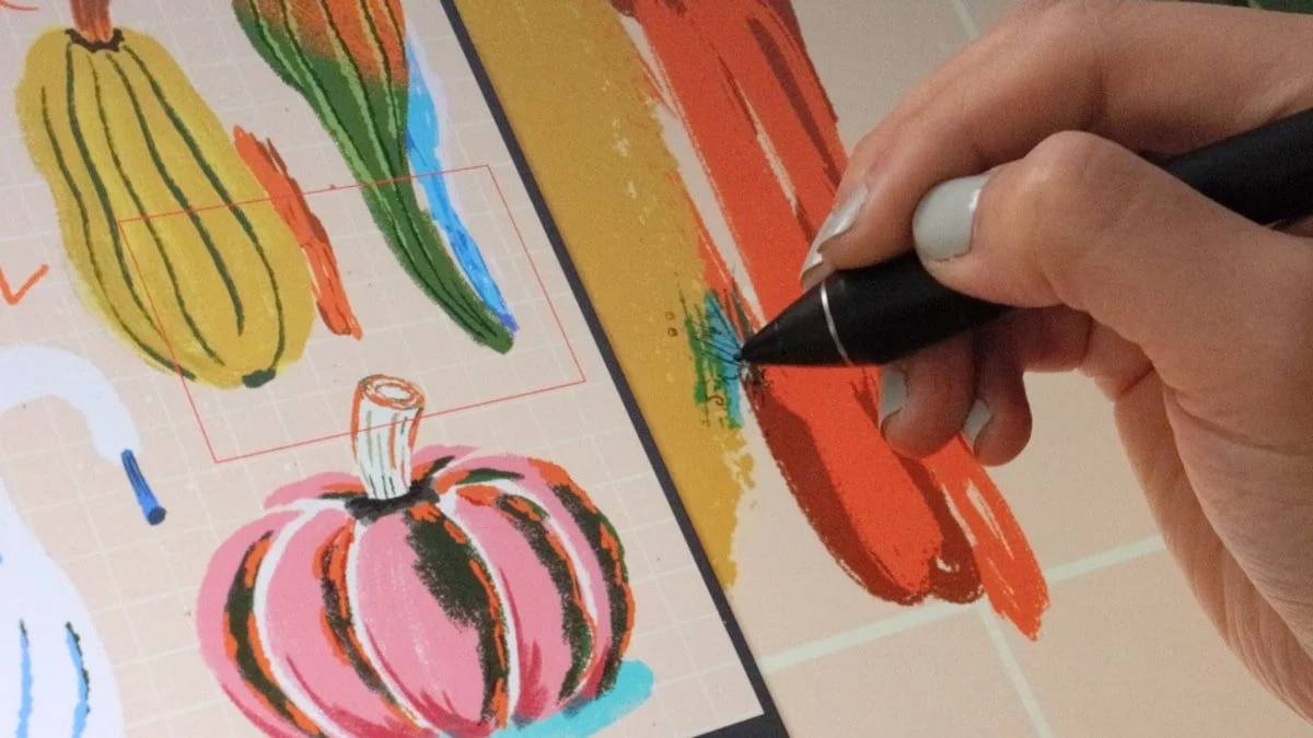 Hand drawing colorful gourds and a pink pumpkin on a pen display tablet, refining textured digital brushstrokes.