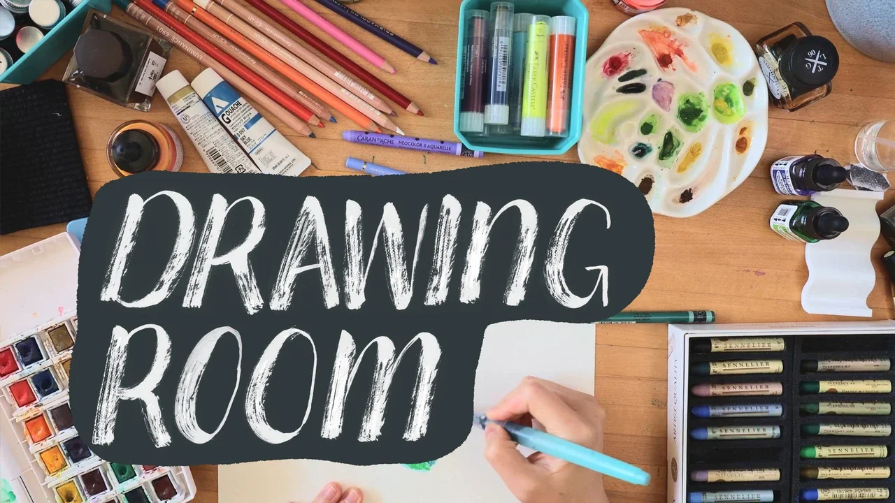 A cluttered wooden desk with art supplies, including watercolors, colored pencils, markers, ink bottles, and a paint palette. A hand is drawing on a sheet of paper, and a sign reads 'Drawing Room'.