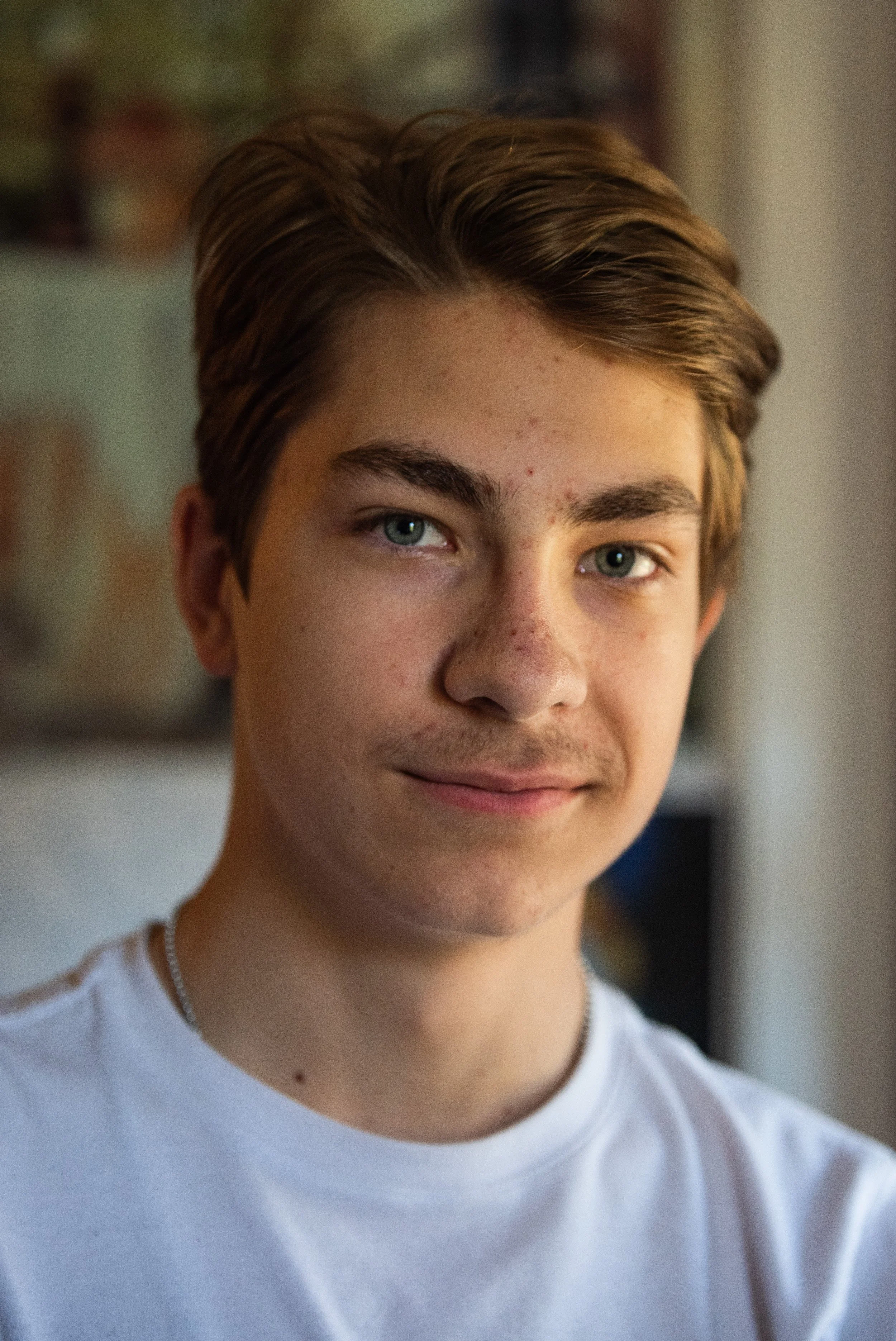 Close-up of a young man's face, showing his eyes, eyebrows, and part of his nose and mouth, with a blurred background.