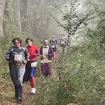 Group of runners participating in a trail race through a foggy forest.