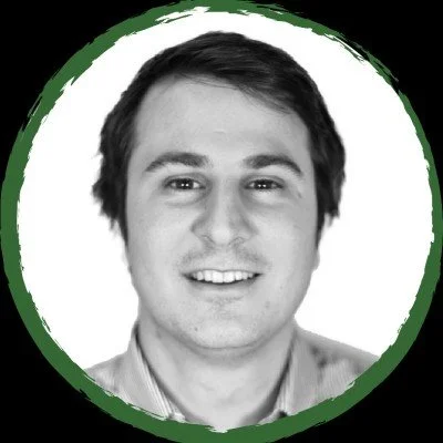 Black and white portrait of a smiling young man with short dark hair, framed by a green circular border.