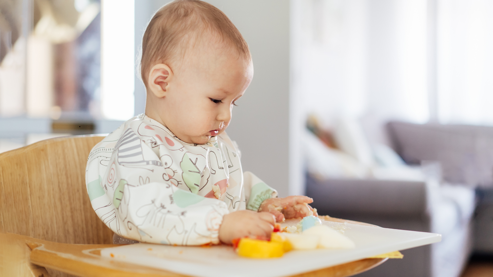 Baby exploring soft finger foods in a high chair to develop chewing skills and confidence when starting solids