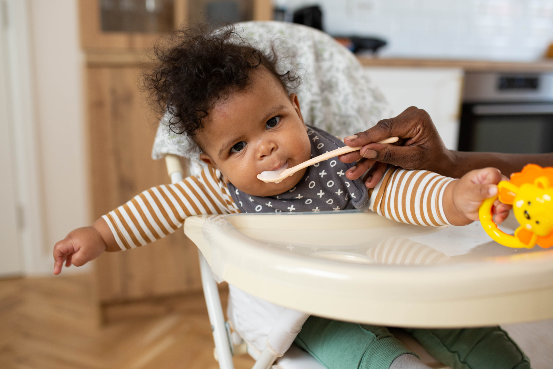 Parent supporting baby during first solid foods with calm, responsive feeding approach