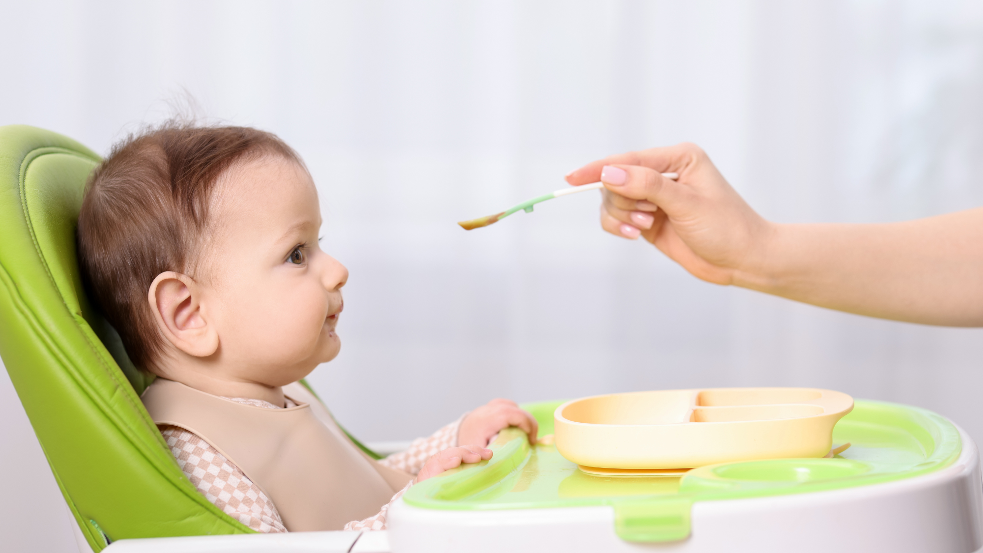 Caregiver feeding a young child during a calm mealtime, illustrating responsive feeding and supportive parent-child interaction.