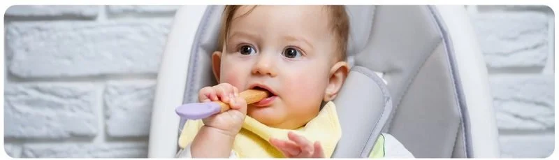 Baby holding a spoon in a highchair