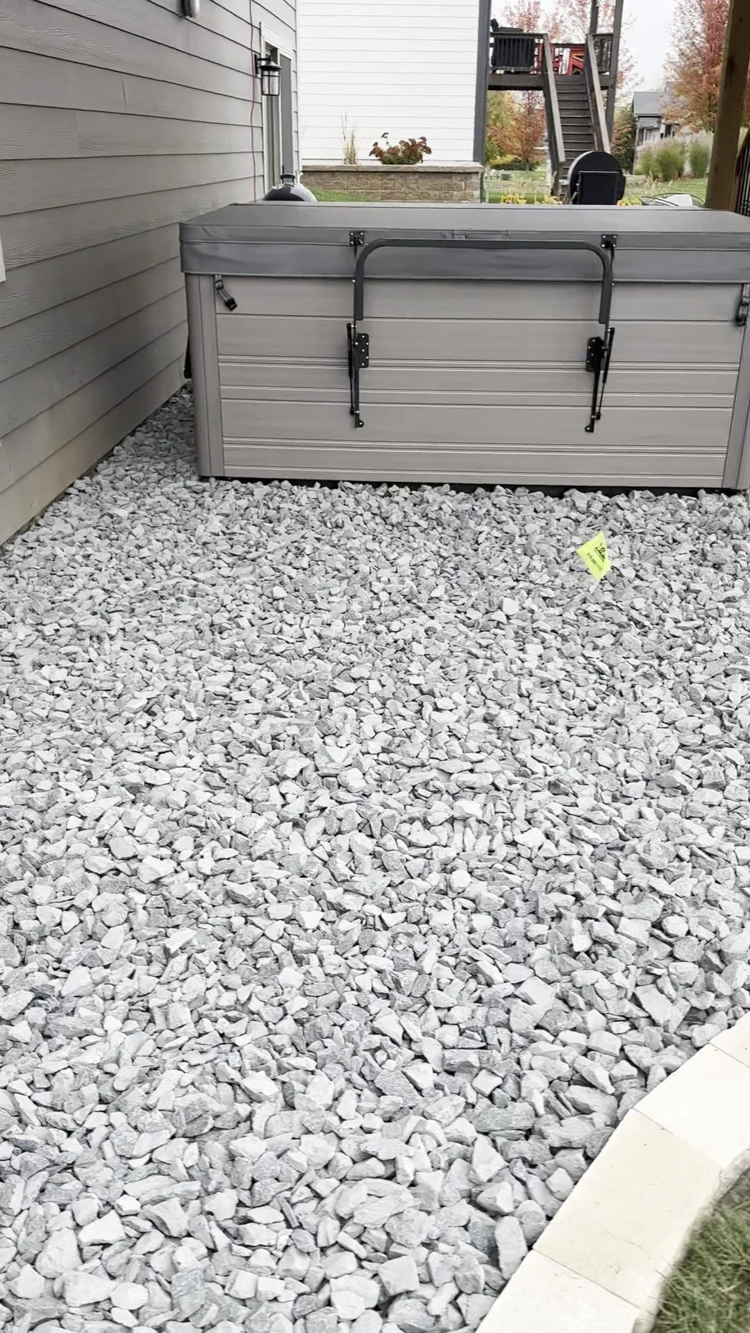 Outdoor hot tub on gravel surface near a building.
