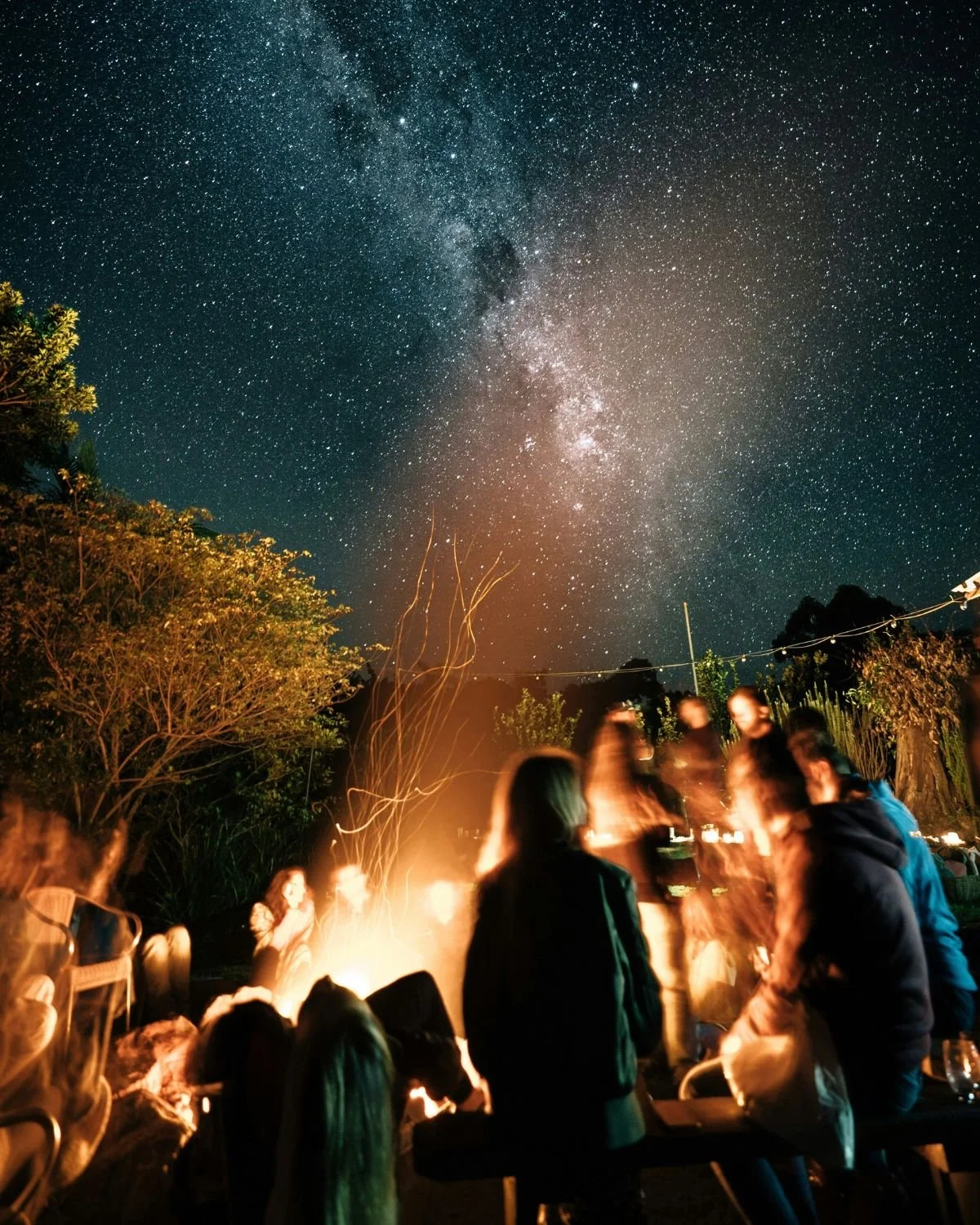 People sitting around a fire with the Milky Way overhead