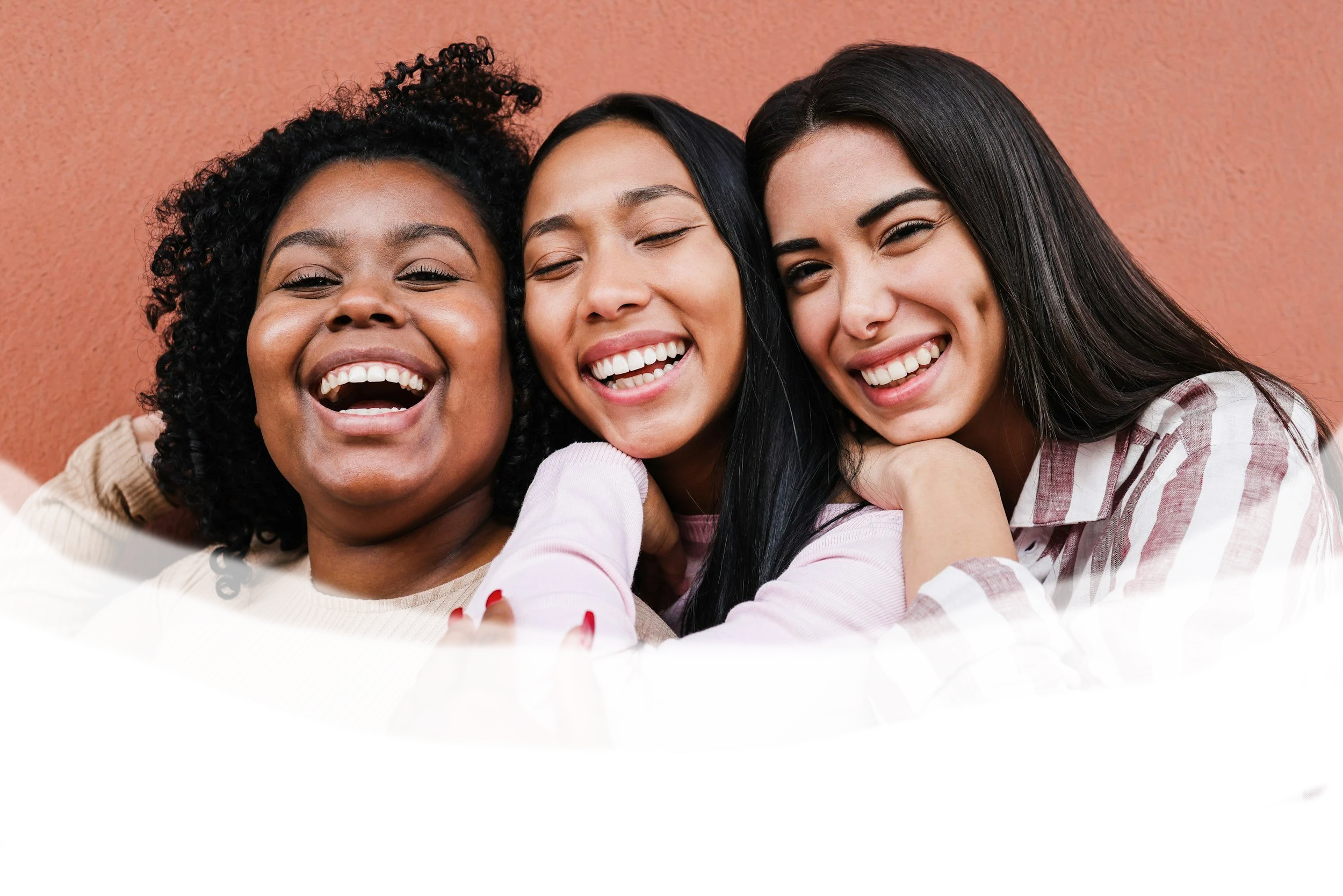 Group of diverse women smiling and hugging in a casual setting.