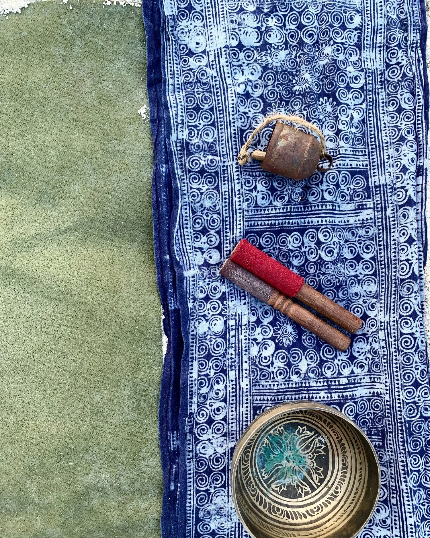 Singing bowl with striker on patterned cloth