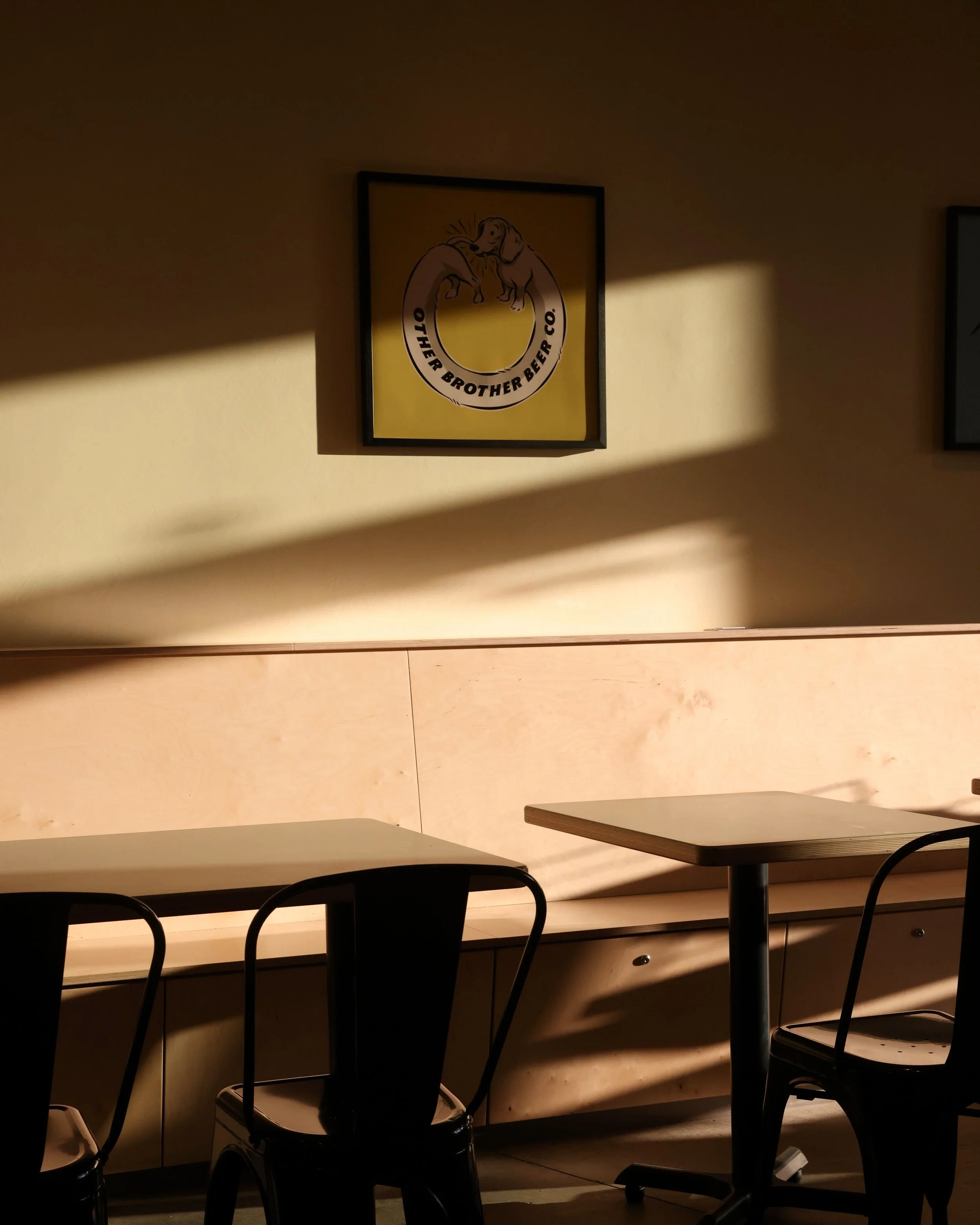 The taproom interior for other brother beer co located in aptos with tables, chairs, and a bench with afternoon lighting