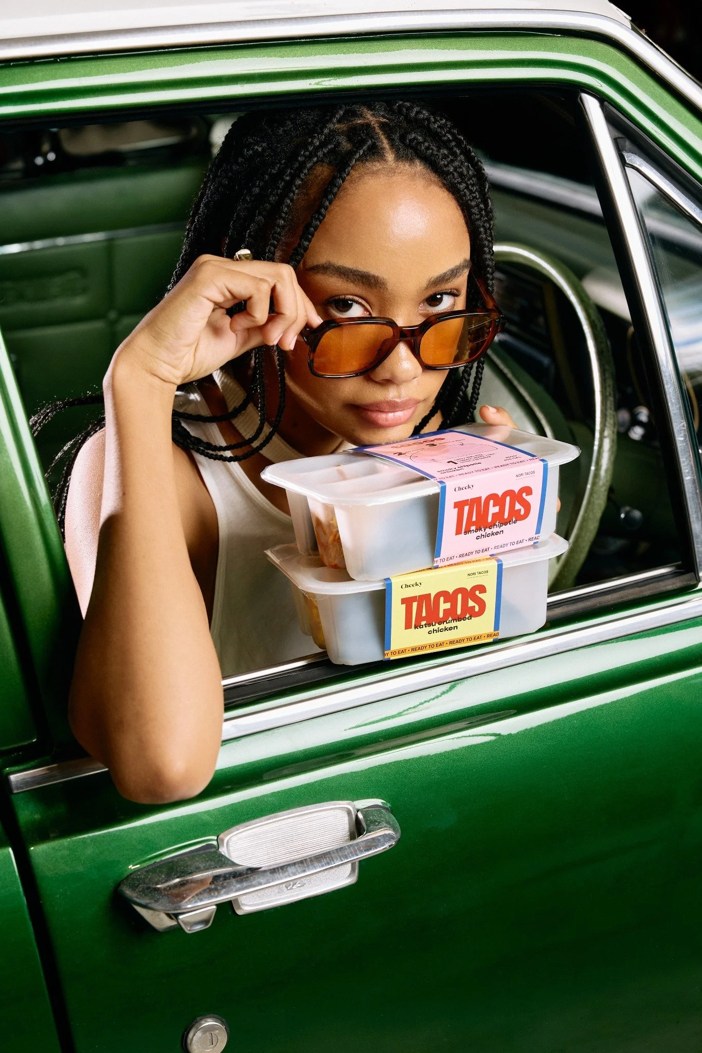 Cheeky packaged tacos held through the window of a green car