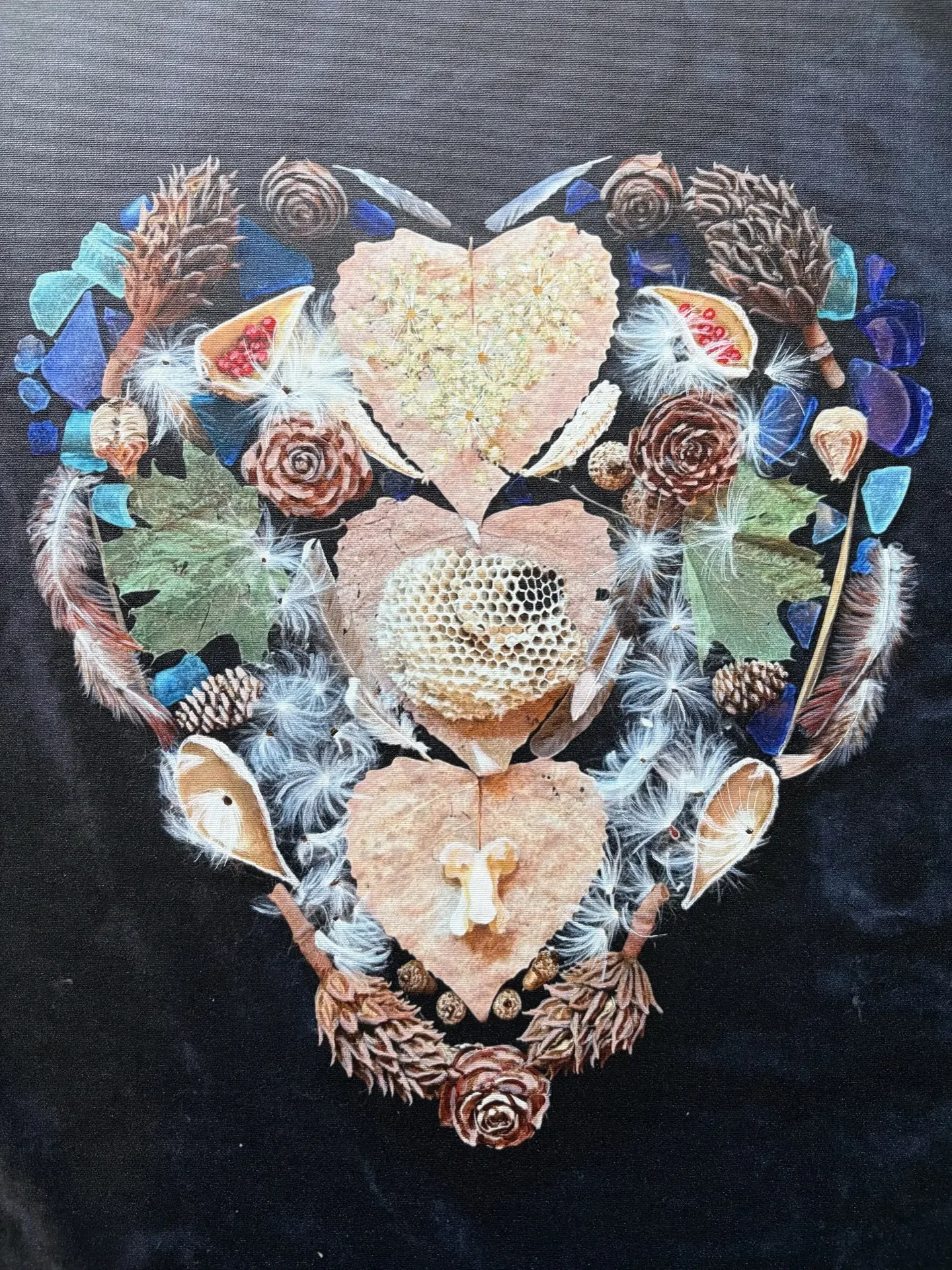 Heart-shaped ephemeral artwork made from feathers, leaves, seed pods, and blue glass by Chiara D’Amore