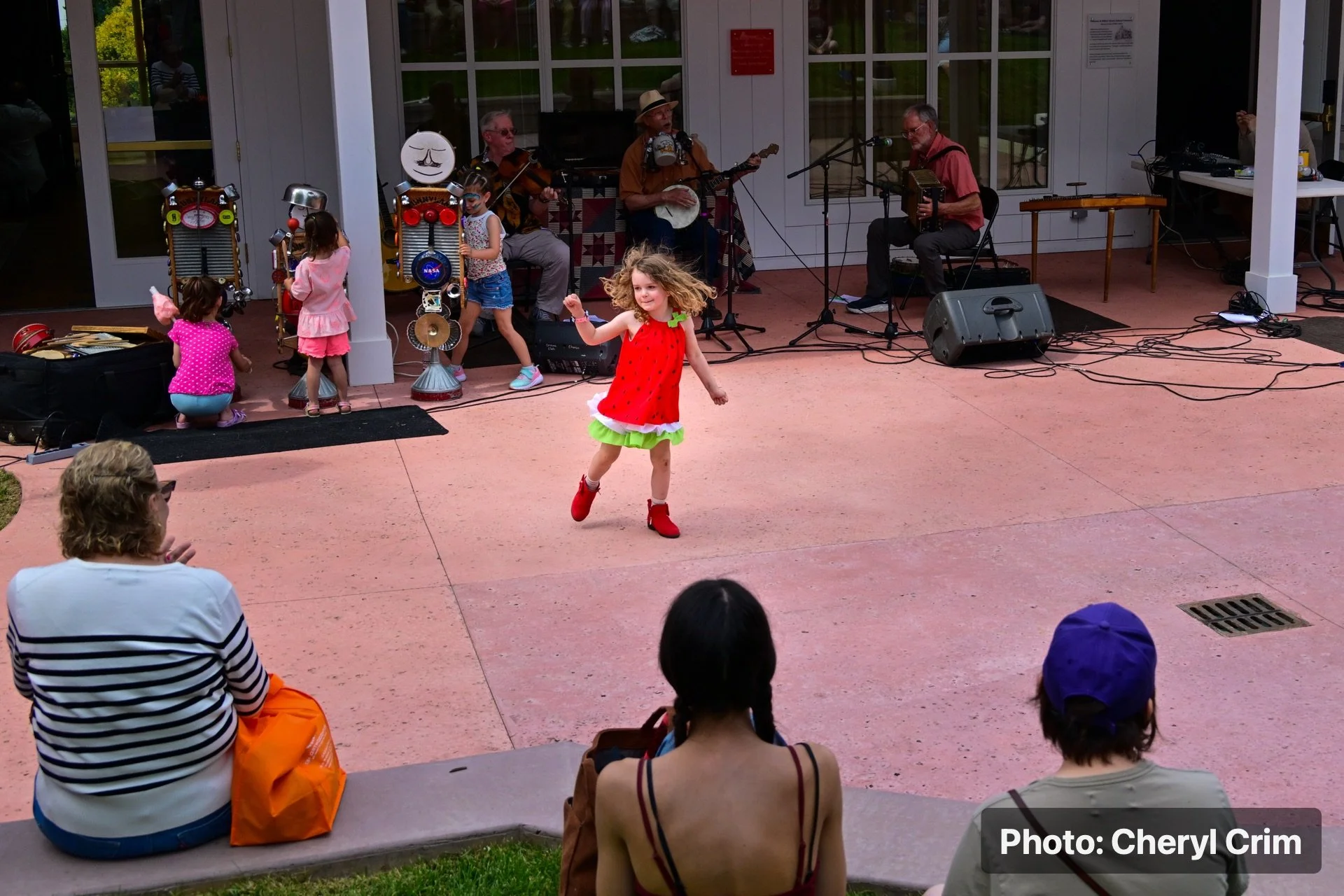 Children dancing near an outdoor stage during the Strawberry Festival.