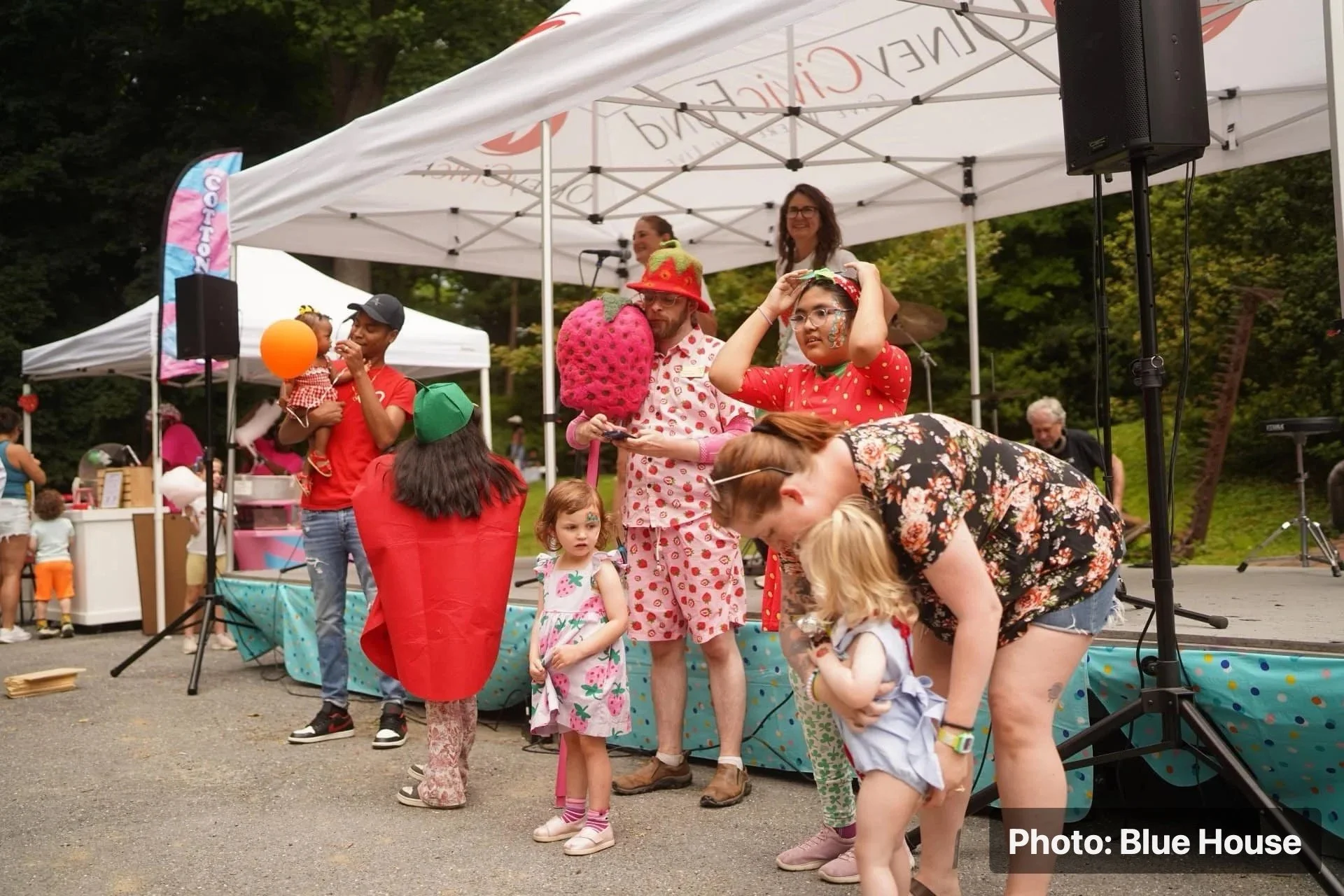 Children and families gathered near a stage for strawberry-themed festival activities.