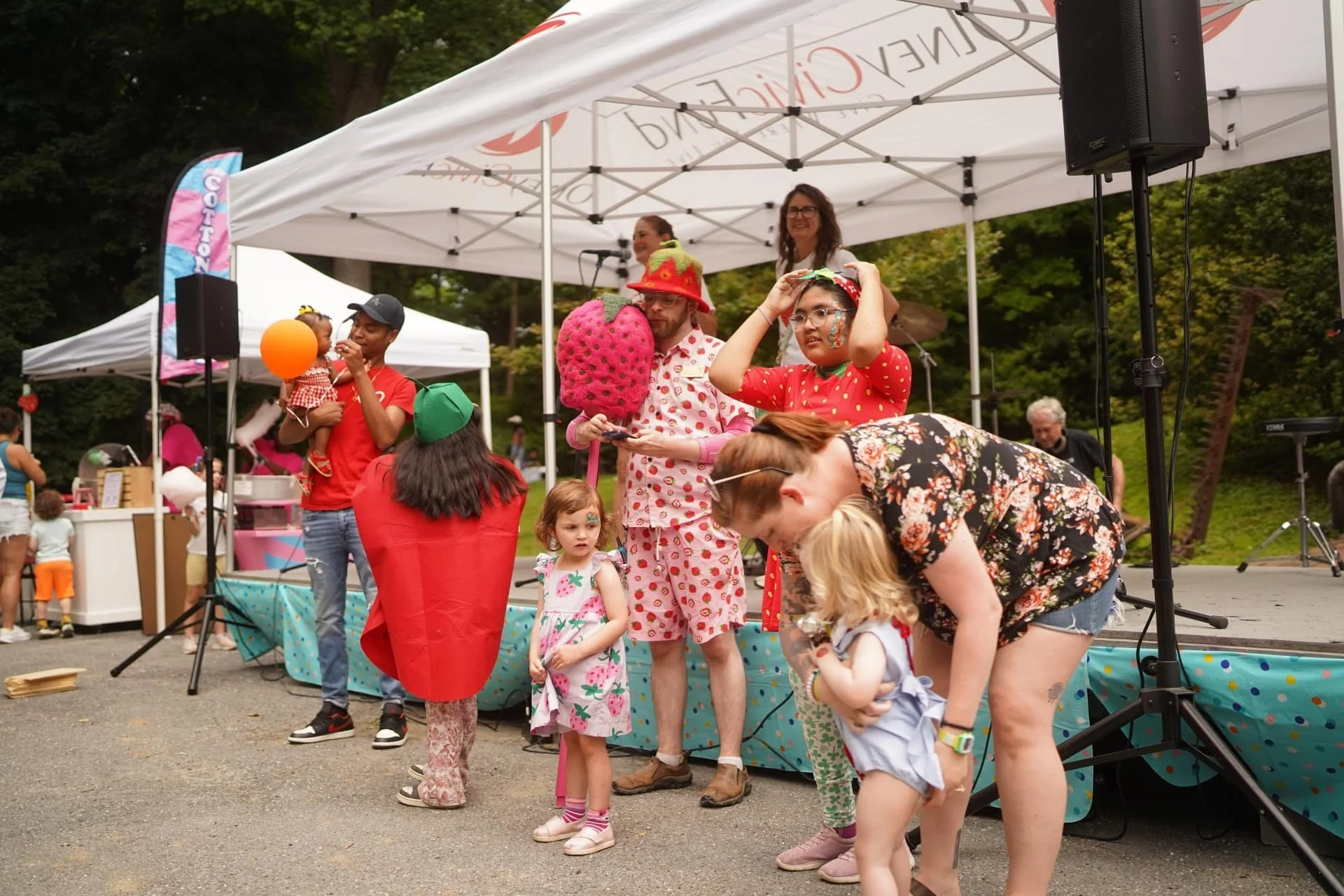 Children and families gathered near a stage for strawberry-themed festival activities.