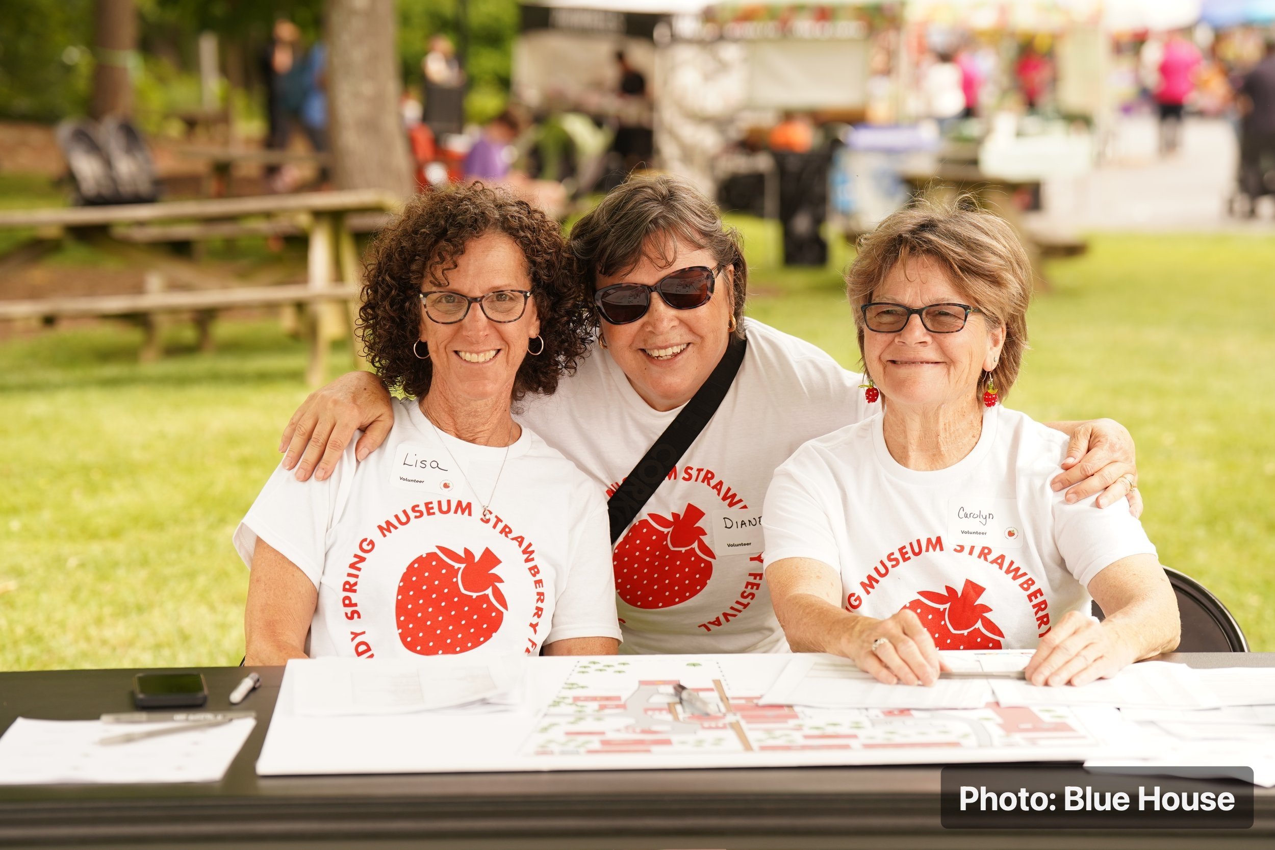 Three Strawberry Festival volunteers are staffing the admissions table and welcoming visitors