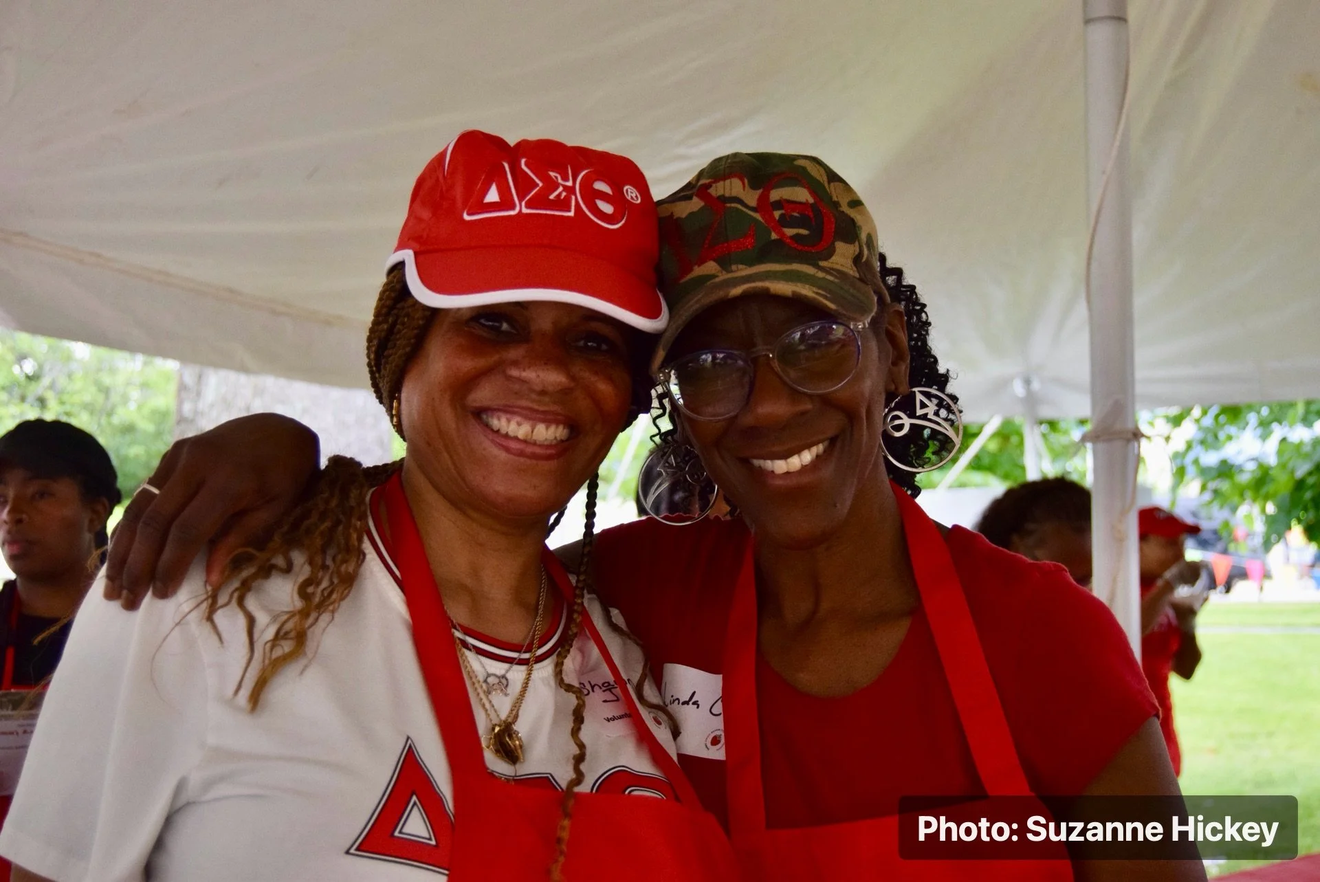 Two smiling people posing together under a tent at the Strawberry Festival.