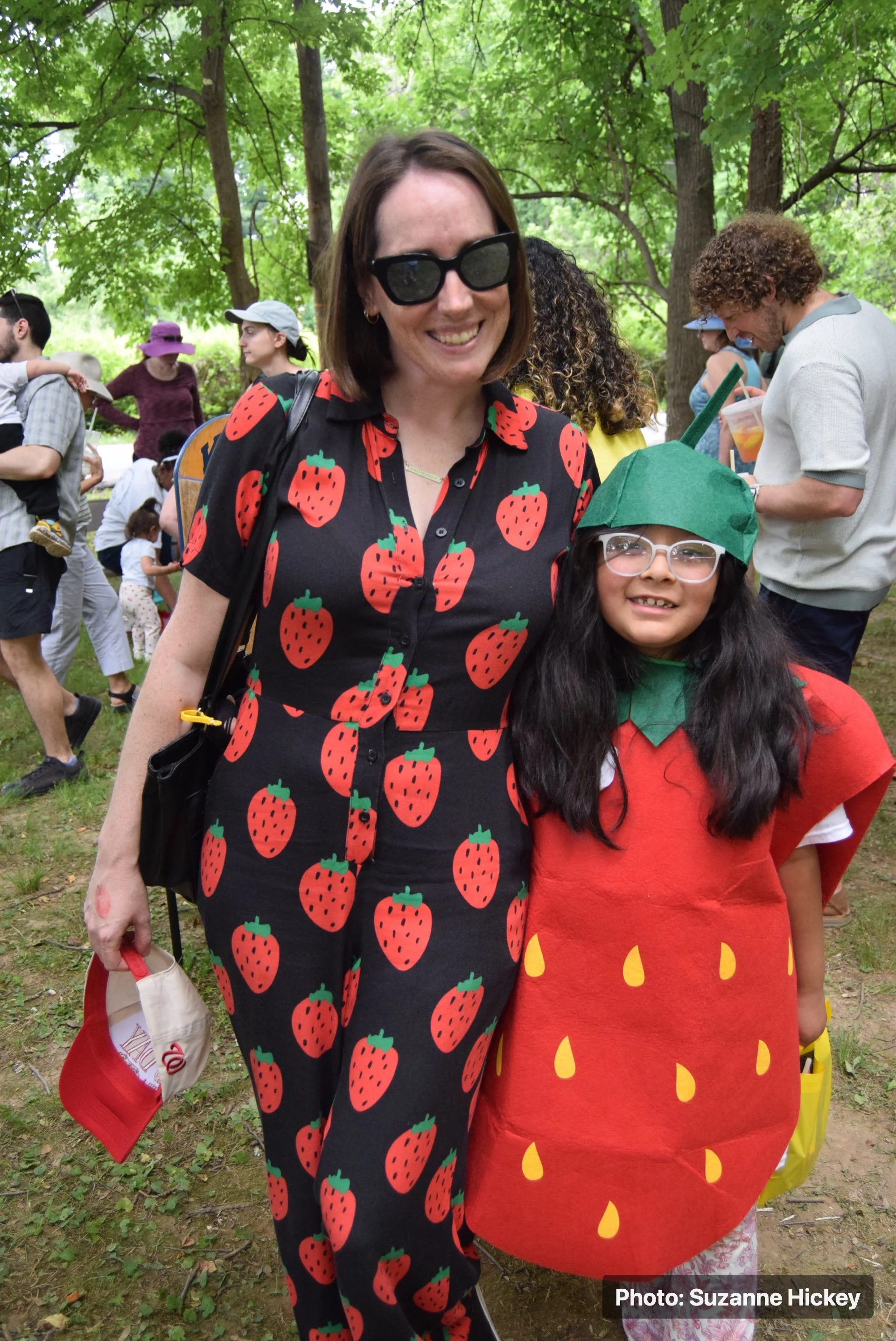 An adult and child wearing strawberry-themed outfits at the Strawberry Festival.