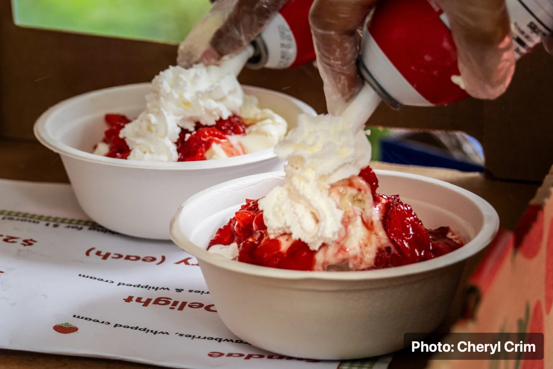 Strawberry shortcake being topped with whipped cream at the Strawberry Festival.