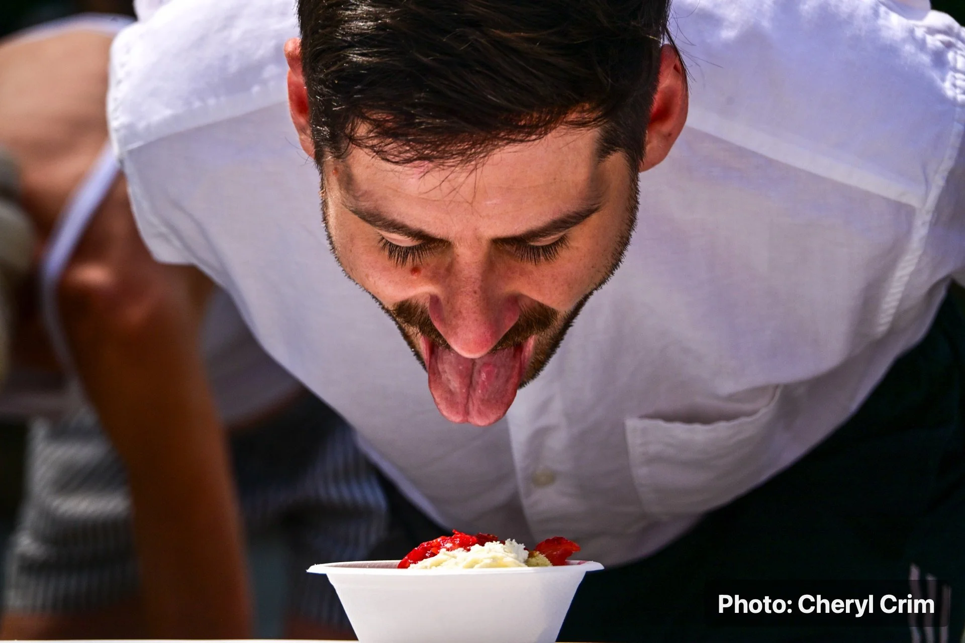 A festival attendee eating strawberry shortcake during the Strawberry Festival.
