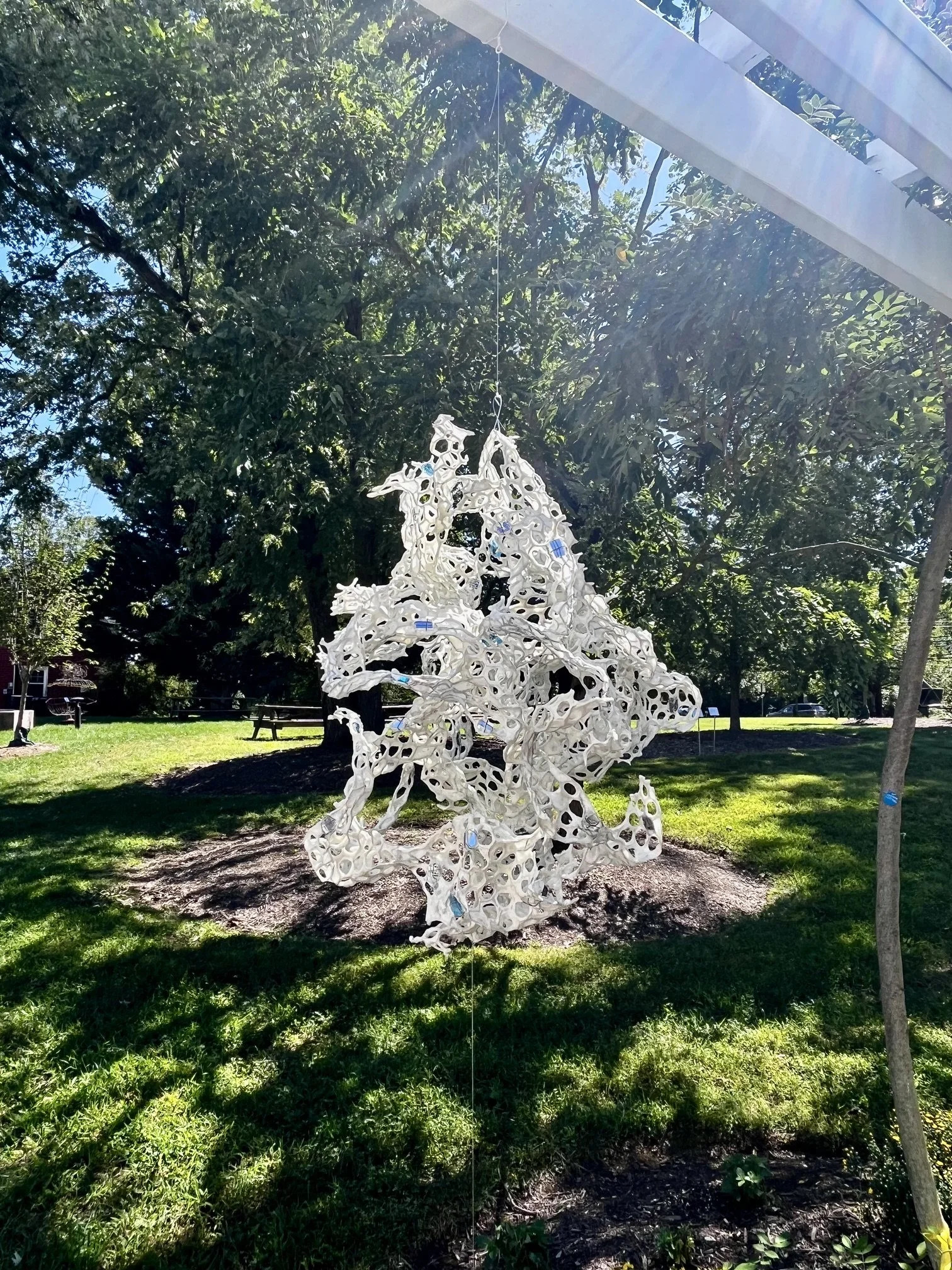 White openwork sculpture suspended outdoors at Sandy Spring Museum.