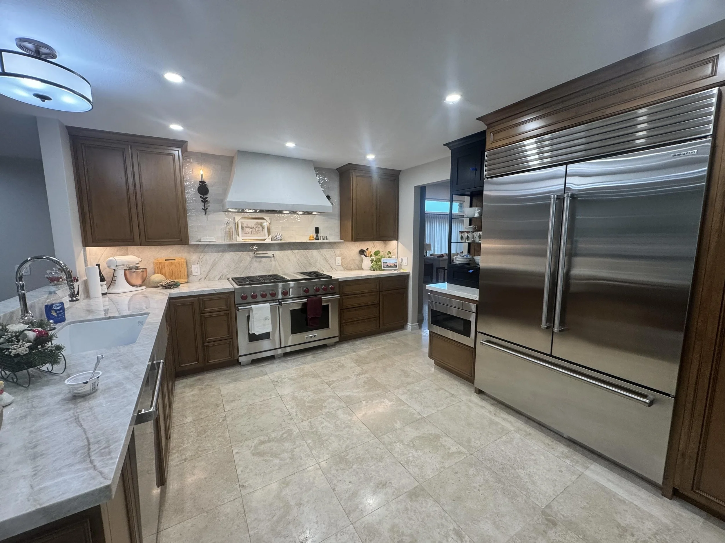 This Thousand Oaks kitchen remodel required a reconfiguration of the cabinetry footprint to support a new 48 inch Sub-Zero refrigerator and 48 inch Wolf range. The flooring is travertine and the counters and backsplash are Taj Mahal quartzite. This b