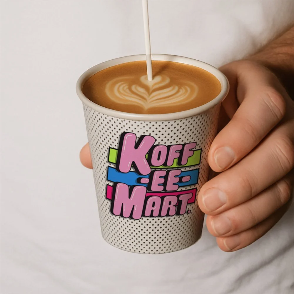 Hand holding a cup of coffee with latte art, a heart design, and a colorful