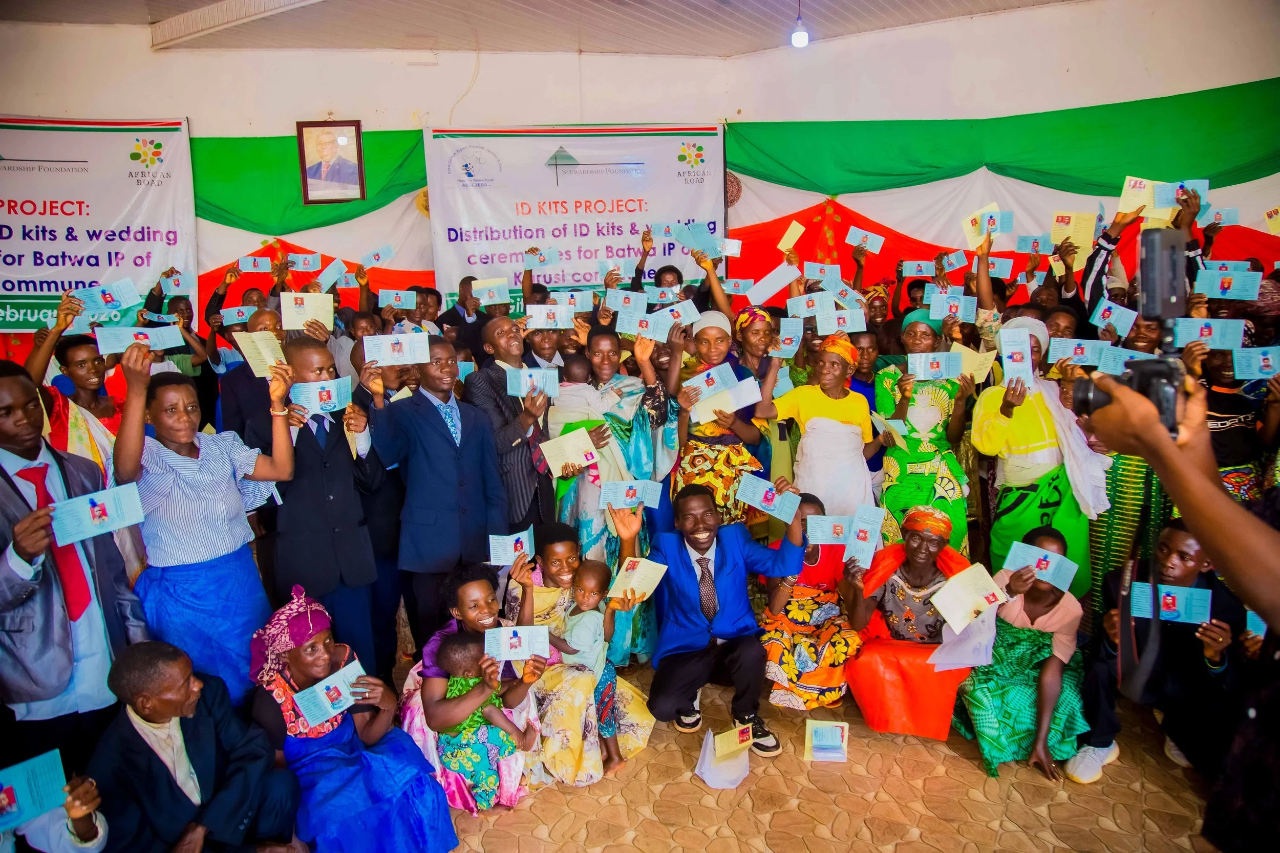 Batwa people smiling holding ID cards