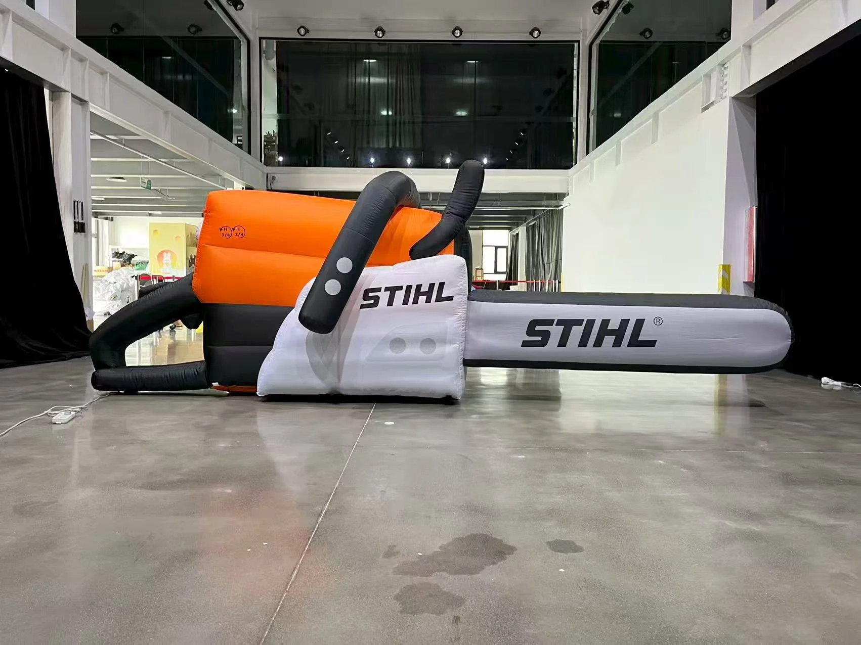 Giant inflatable Stihl chainsaw product replica displayed indoors at an exhibition venue