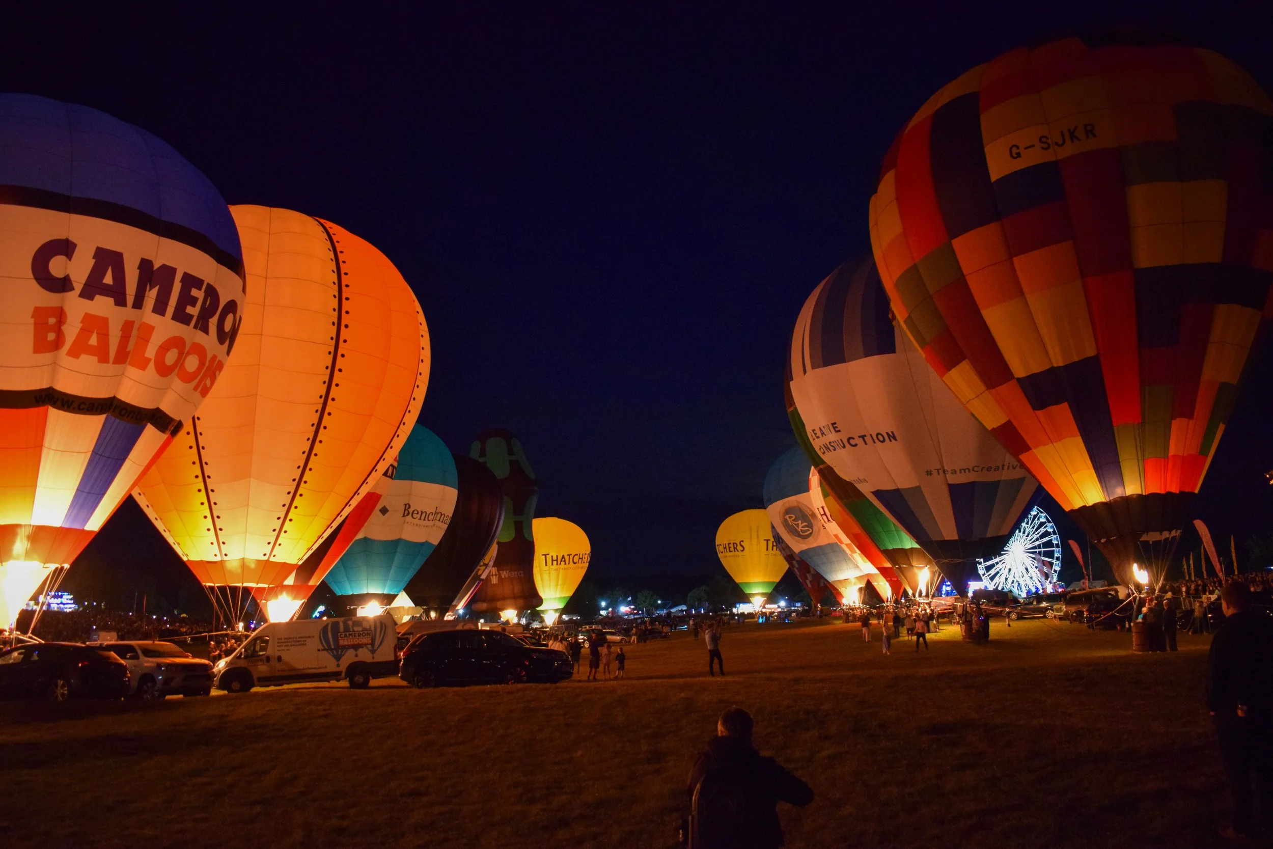 Hot air balloons inflated at night at the Bristol International Balloon Fiesta including Cameron Balloons