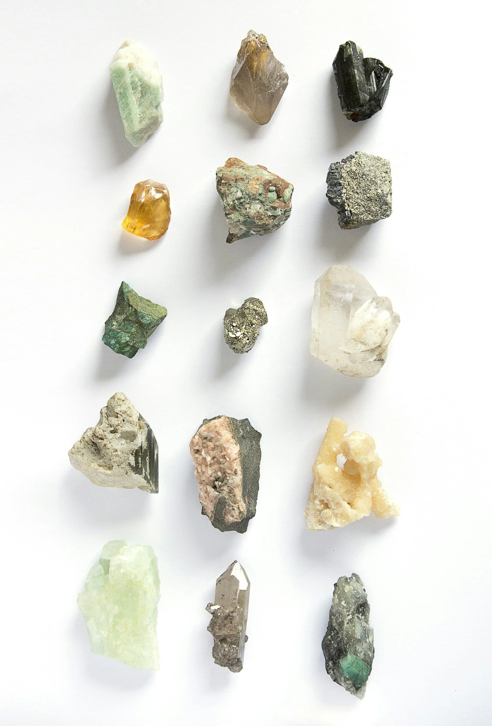 A collection of 15 different mineral and gemstone samples arranged on a white background.