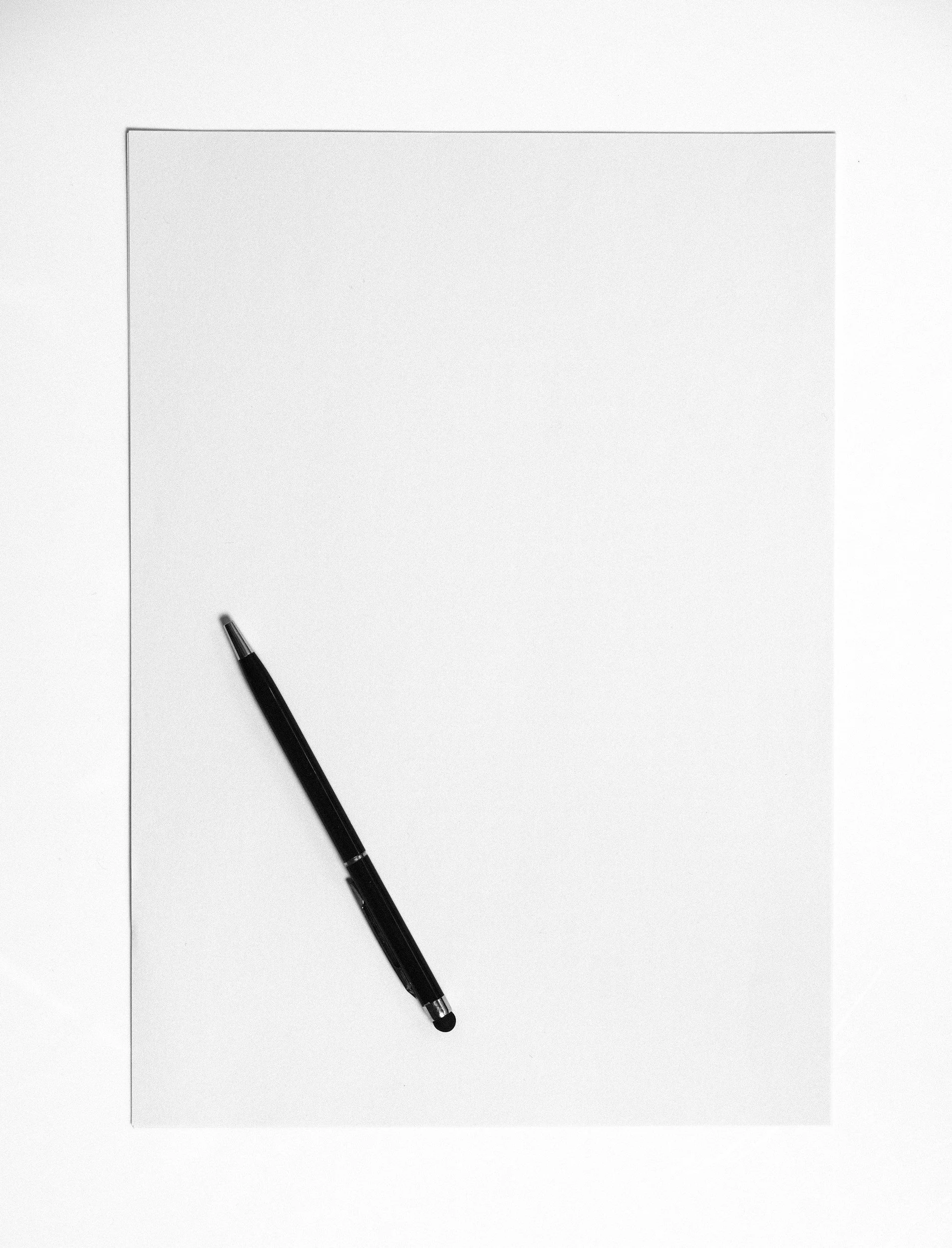 A blank sheet of paper with a black pen resting diagonally across it.