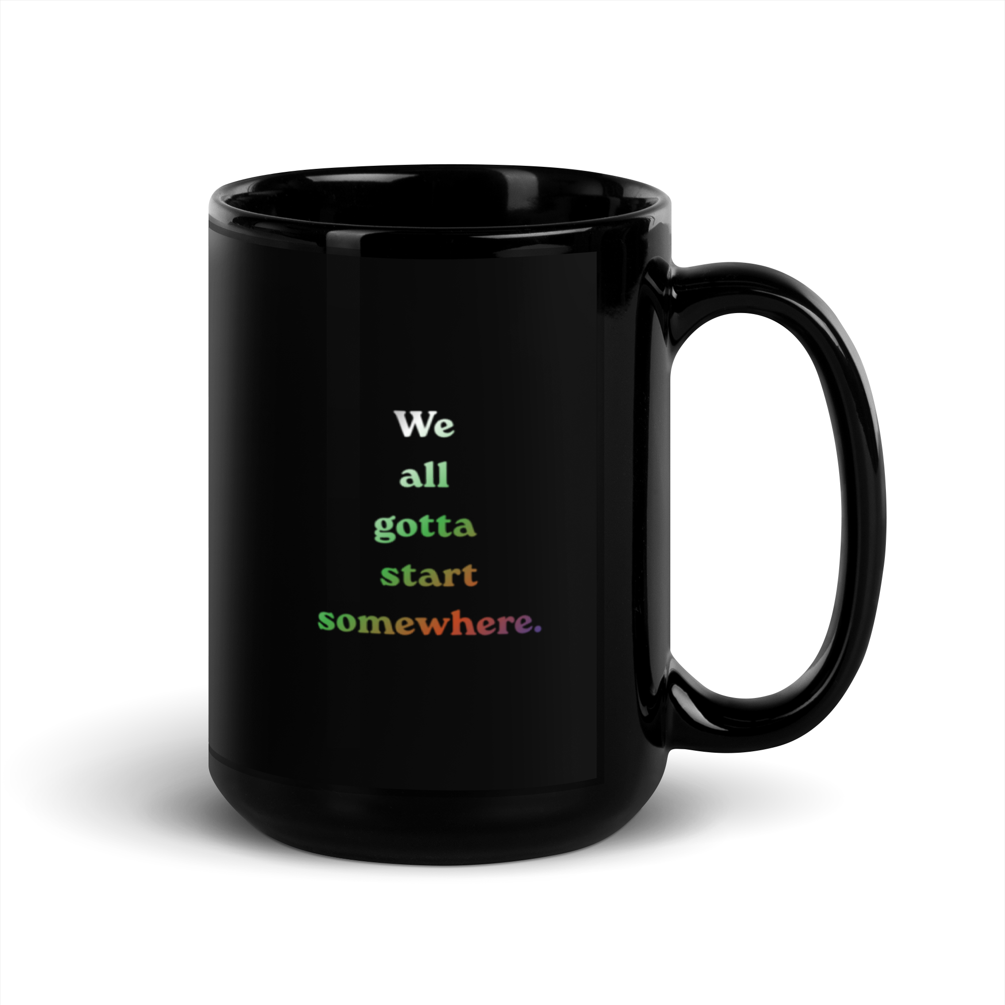 A black coffee mug with the words 'We all gotta start somewhere' written in colorful letters.