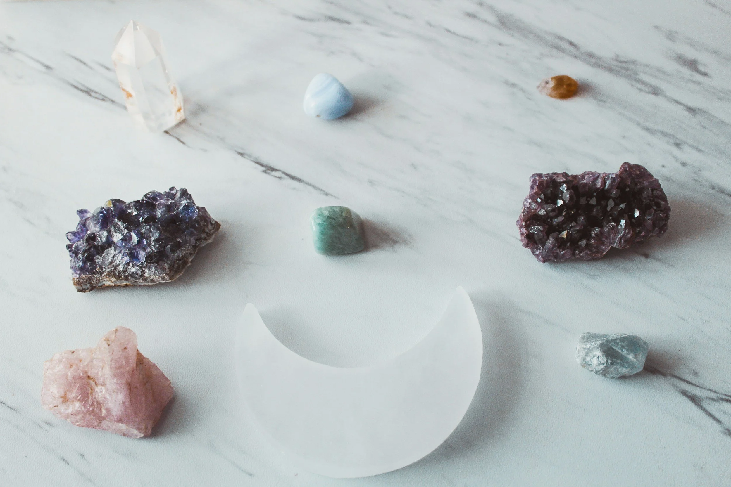 Various colorful mineral and crystal specimens displayed on a white surface.