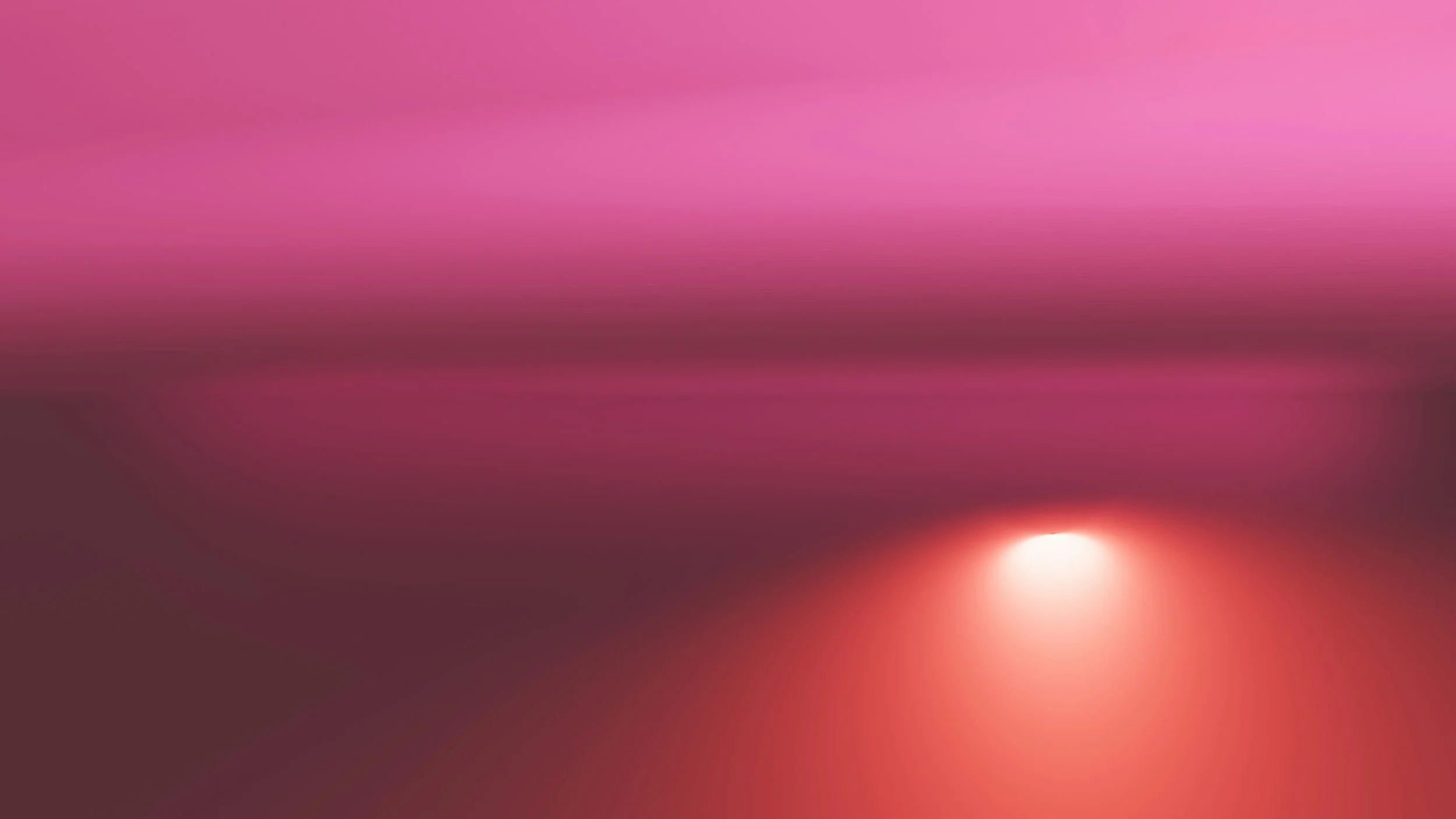 A vibrant sunset or sunrise with a pink and purple sky and the sun partly obscured near the horizon.