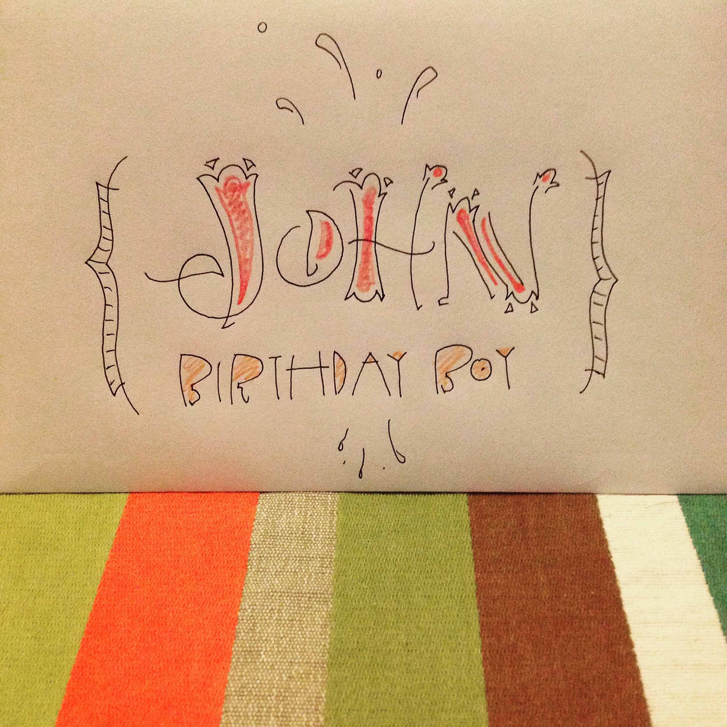Hand-drawn card with "John Birthday Boy" text on a colorful striped background.