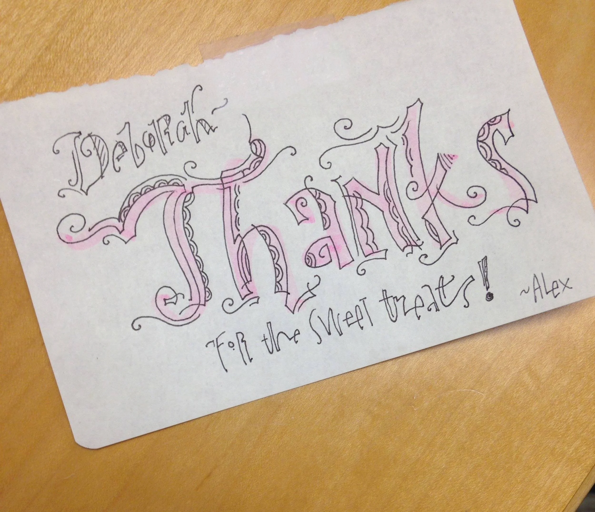 Handwritten note on white paper with calligraphy-style text saying, "Deborah Thanks for the sweet treats! ~Alex" using black and pink ink.