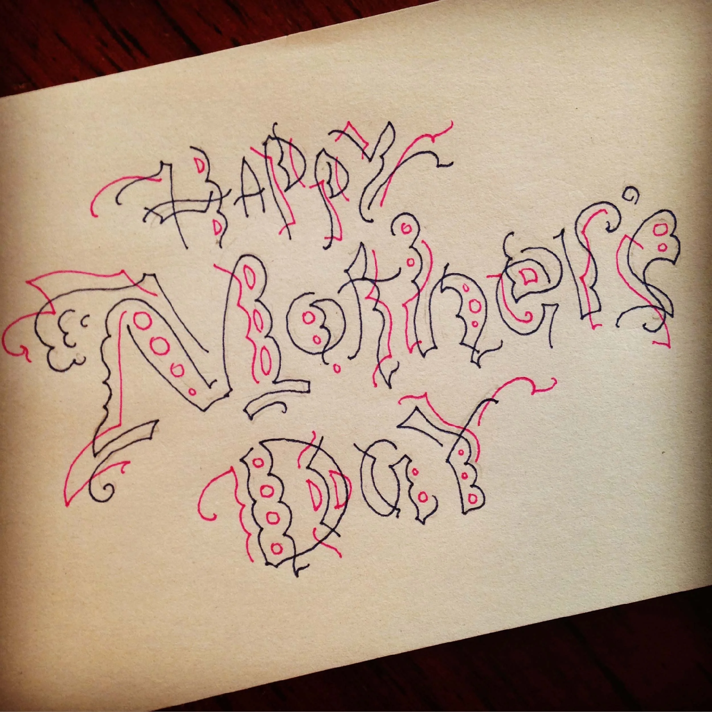 Hand-drawn card with the words "Happy Mother's Day" in decorative, artistic lettering with red and black ink on a white background.