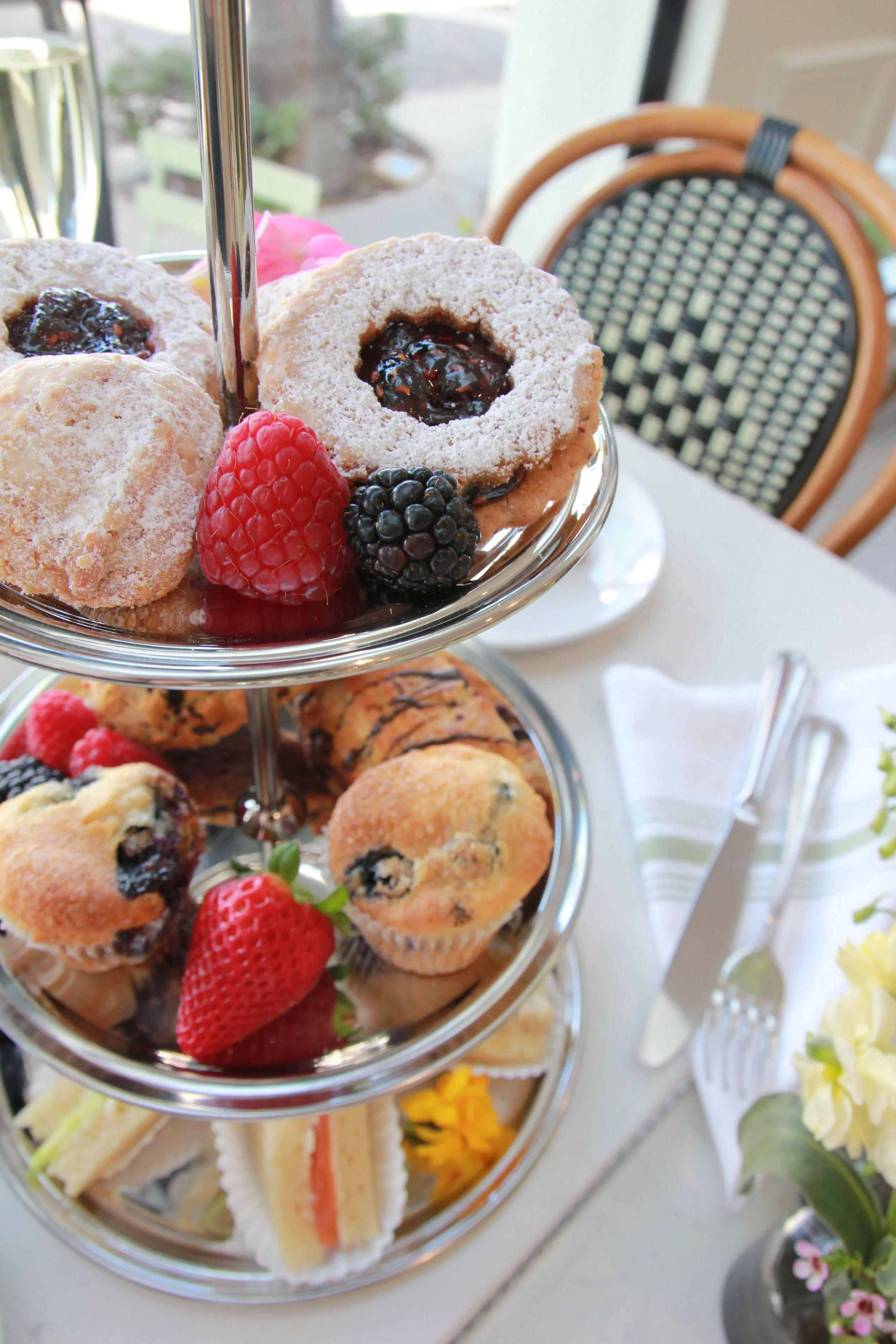 Overhead photo of tea service setup with cookies and sandwiches on a bistro table