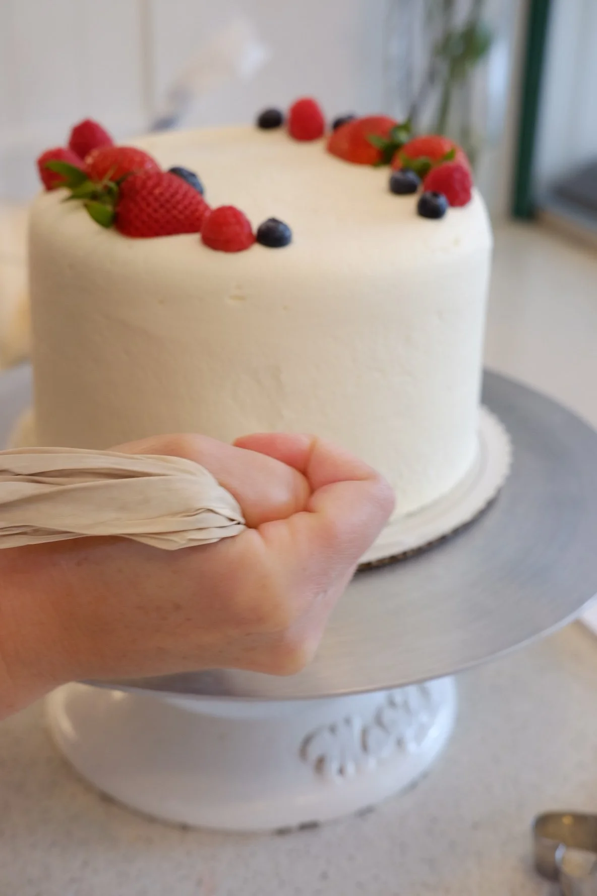 Baker decorating a berry-topped layer cake at Lilac Montecito