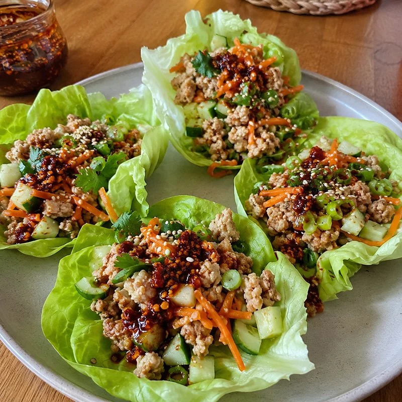 Healthy chili crisp turkey lettuce wraps with lean ground turkey, carrots, cucumber, green onion, herbs, sesame seeds, and spicy chili crisp.
