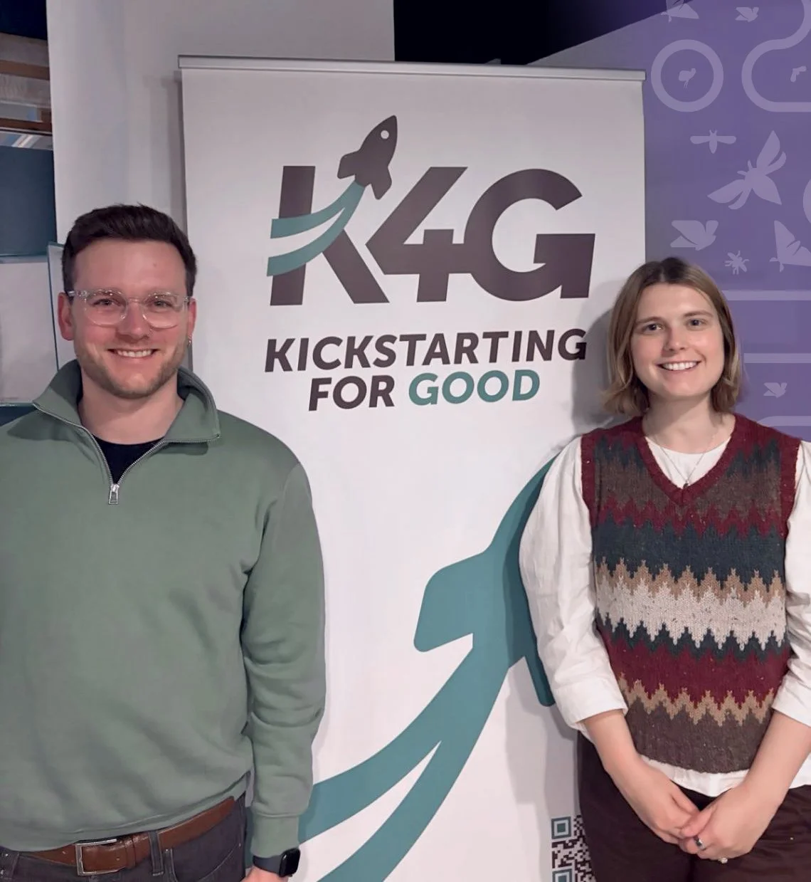 James and Chloë standing next to a banner that reads 'K4G Kickstarting for Good' with a rocket logo.