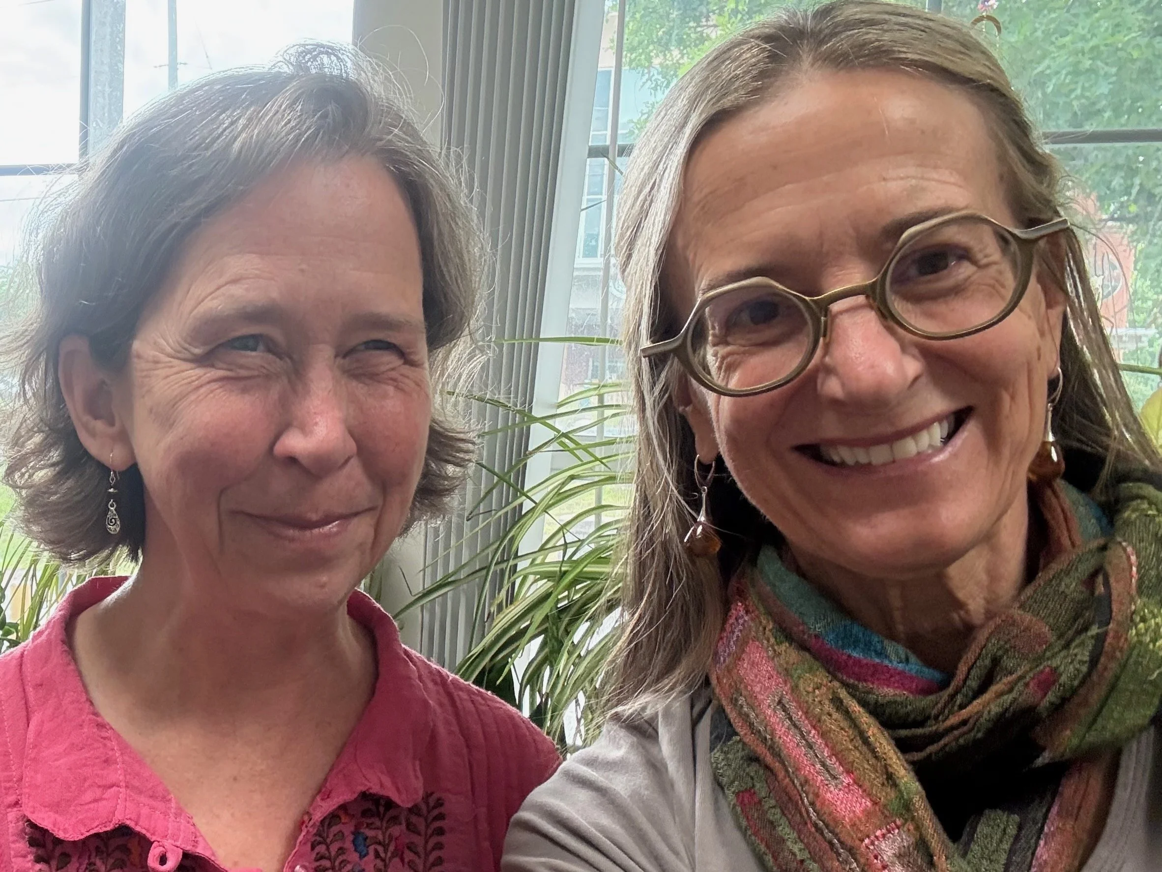 two smiling women in front of window with plants