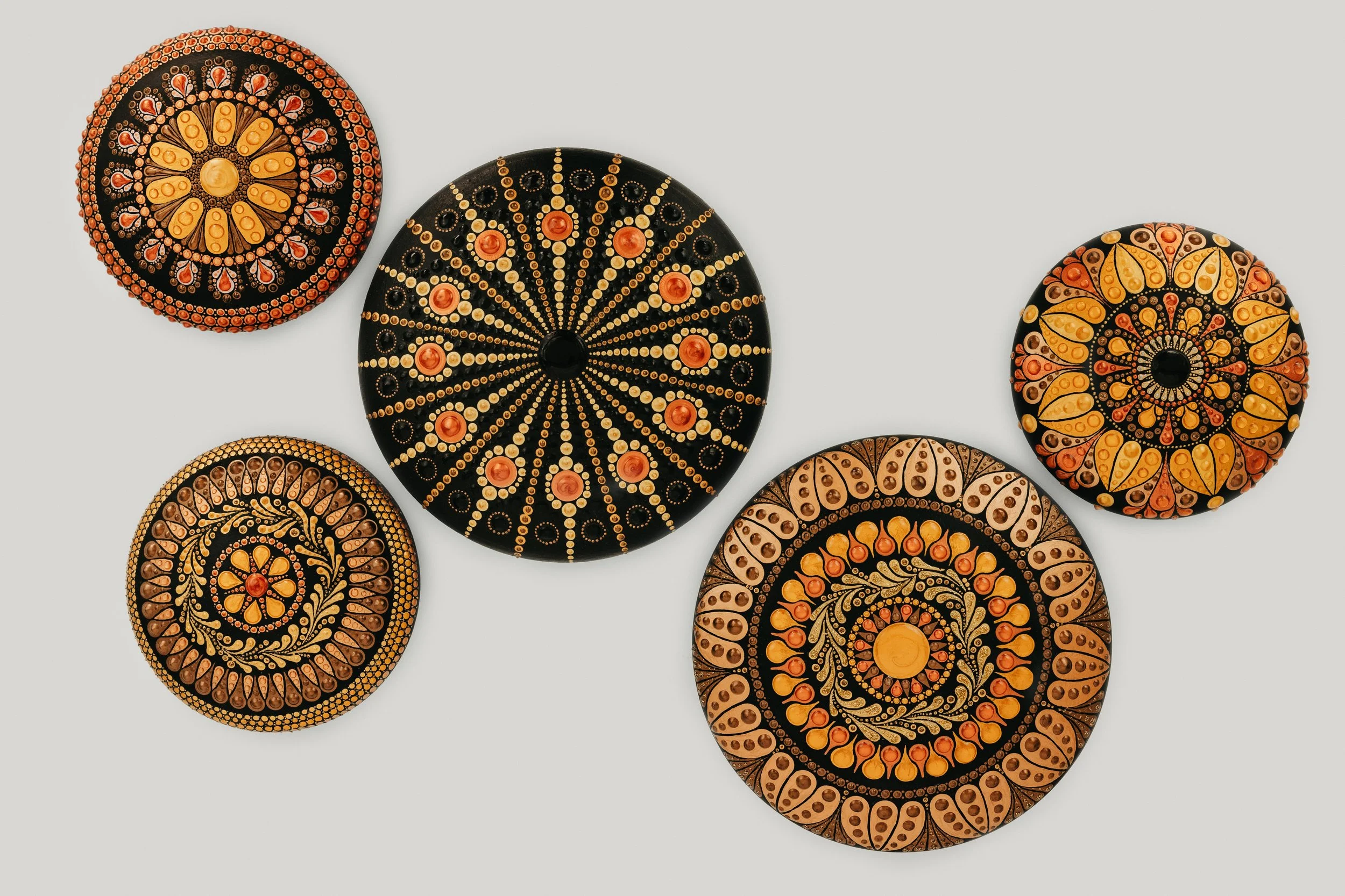 Decorative round objects with intricate patterns in black, orange, yellow, and red colors, arranged on a white background.