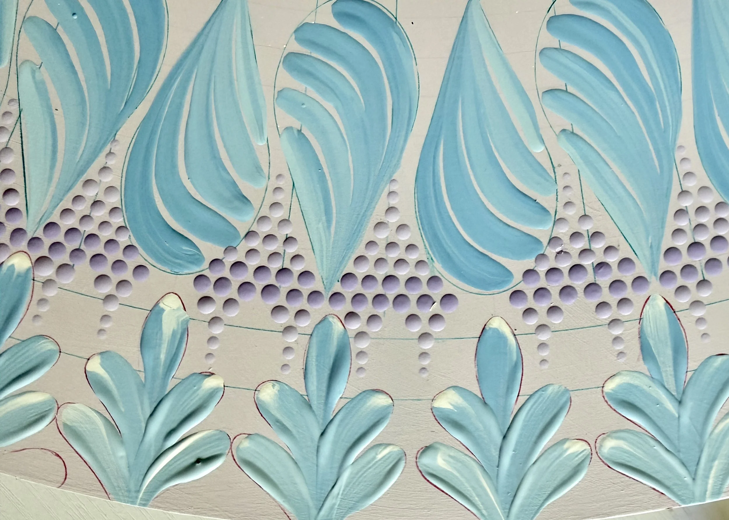 Close-up of a physical art piece featuring painted blue and white overlapping plant leaves on a light background, with perforated holes in the surface.